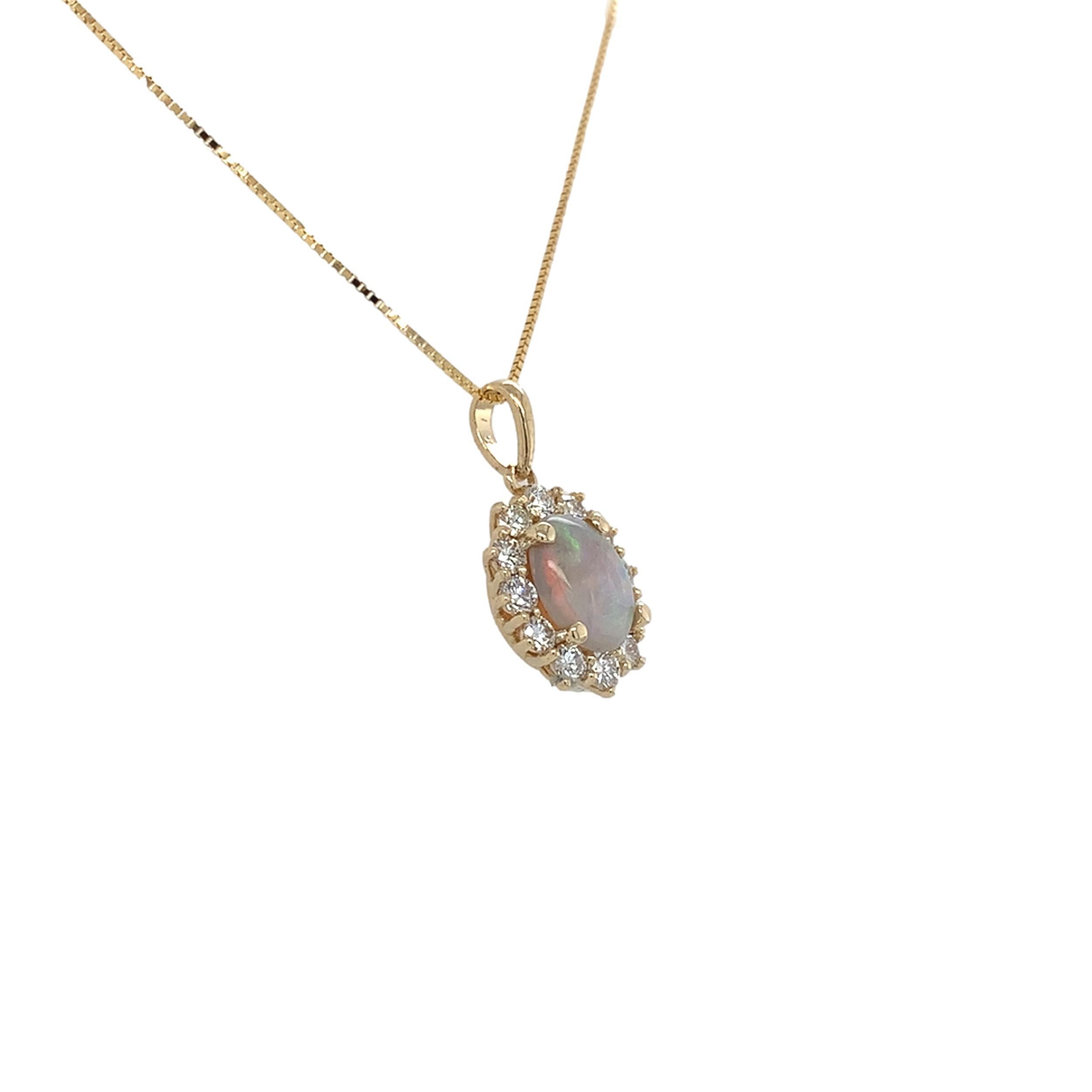 Pendente in oro giallo 14K con opale australiano da 0,67ct e diamanti. L'opale ovale cabochon ha un vibrante gioco di colori con tutti i colori, compreso il rosso.  L'opale naturale estratto dalla terra misura circa 8,5 mm x 6,2 mm. Ci sono 12
