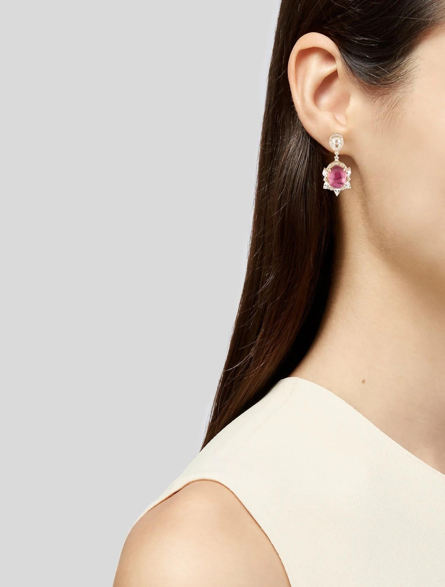 These striking 14K Yellow Gold drop earrings showcase a captivating combination of gemstones, perfect for adding elegance and color to any ensemble. The centerpiece of each earring is a vibrant 9.02 carat oval tourmaline cabochon in a stunning pink