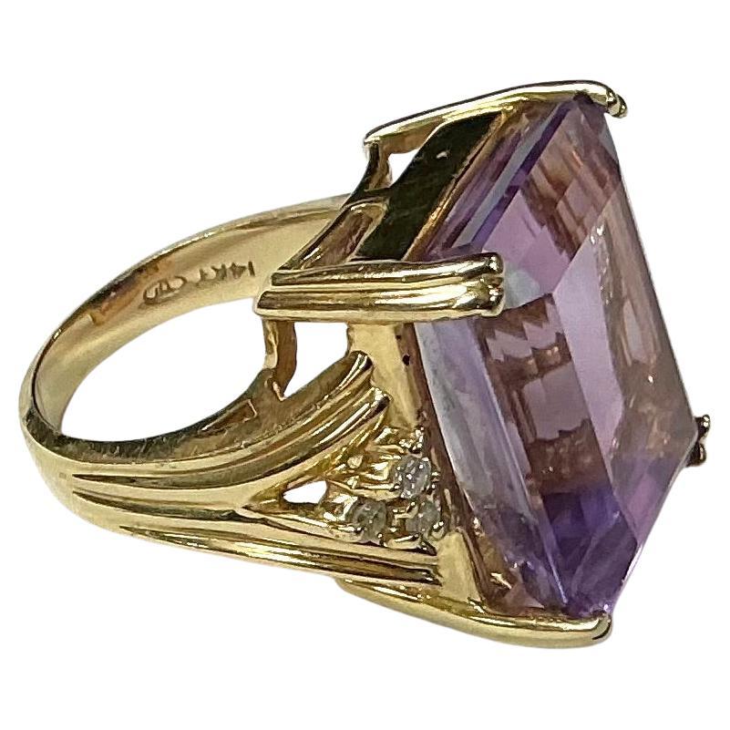 14k Yellow Gold Amethyst and Diamond Ring. 9.8 dwts. The dimensions of the amethyst baguette are approximately 19 mm length x 14 mm width x 6 mm depth. The ring has six round single cut diamonds. Marked 14k and makers brand.