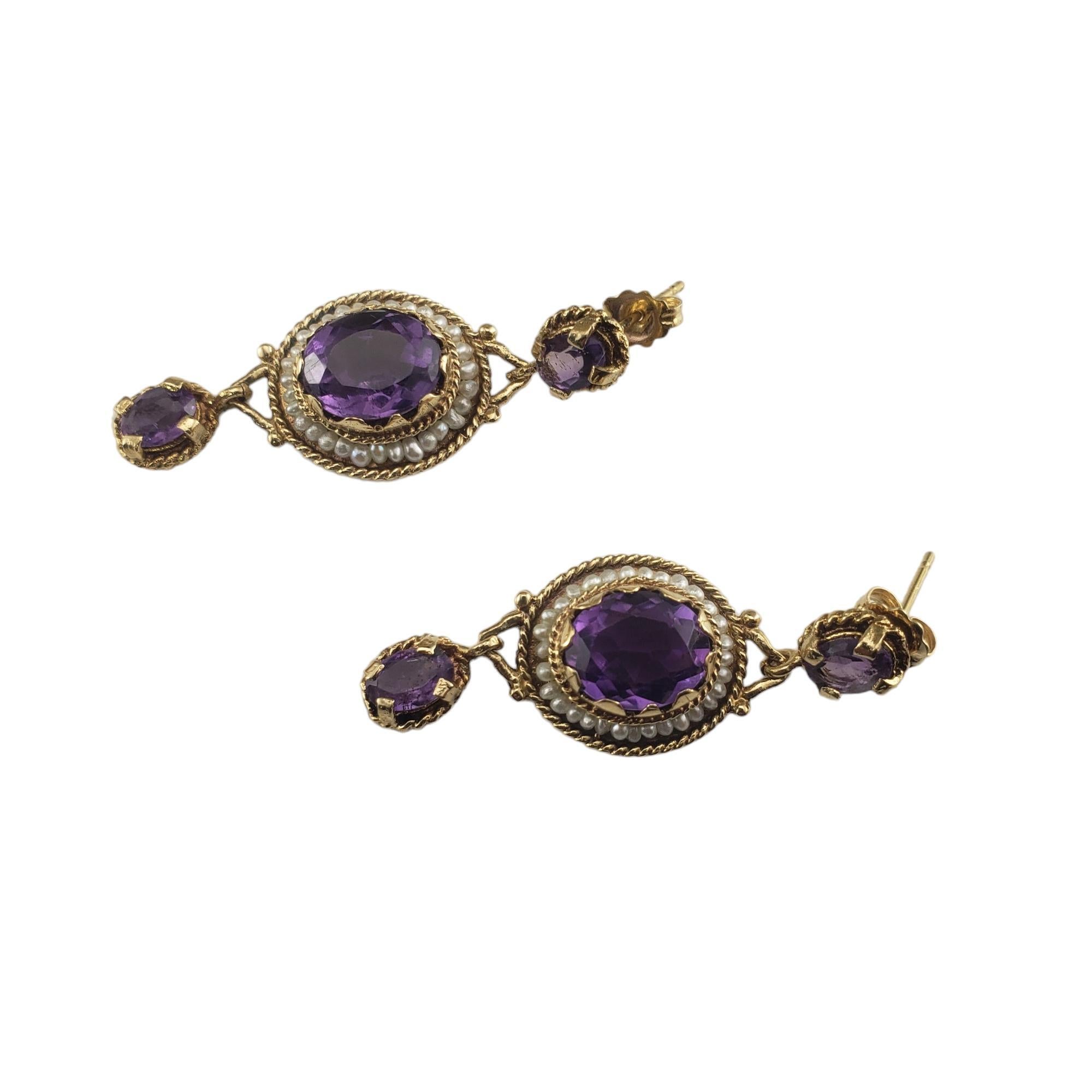 Vintage 14K Yellow Gold Amethyst and Seed Pearl Earrings Lab Certified-

These lovely dangle earrings each features three oval amethyst gemstones and 31 seed pearls set in classic 14K yellow gold.  Push back closures.  

Total amethyst weight:  6.36