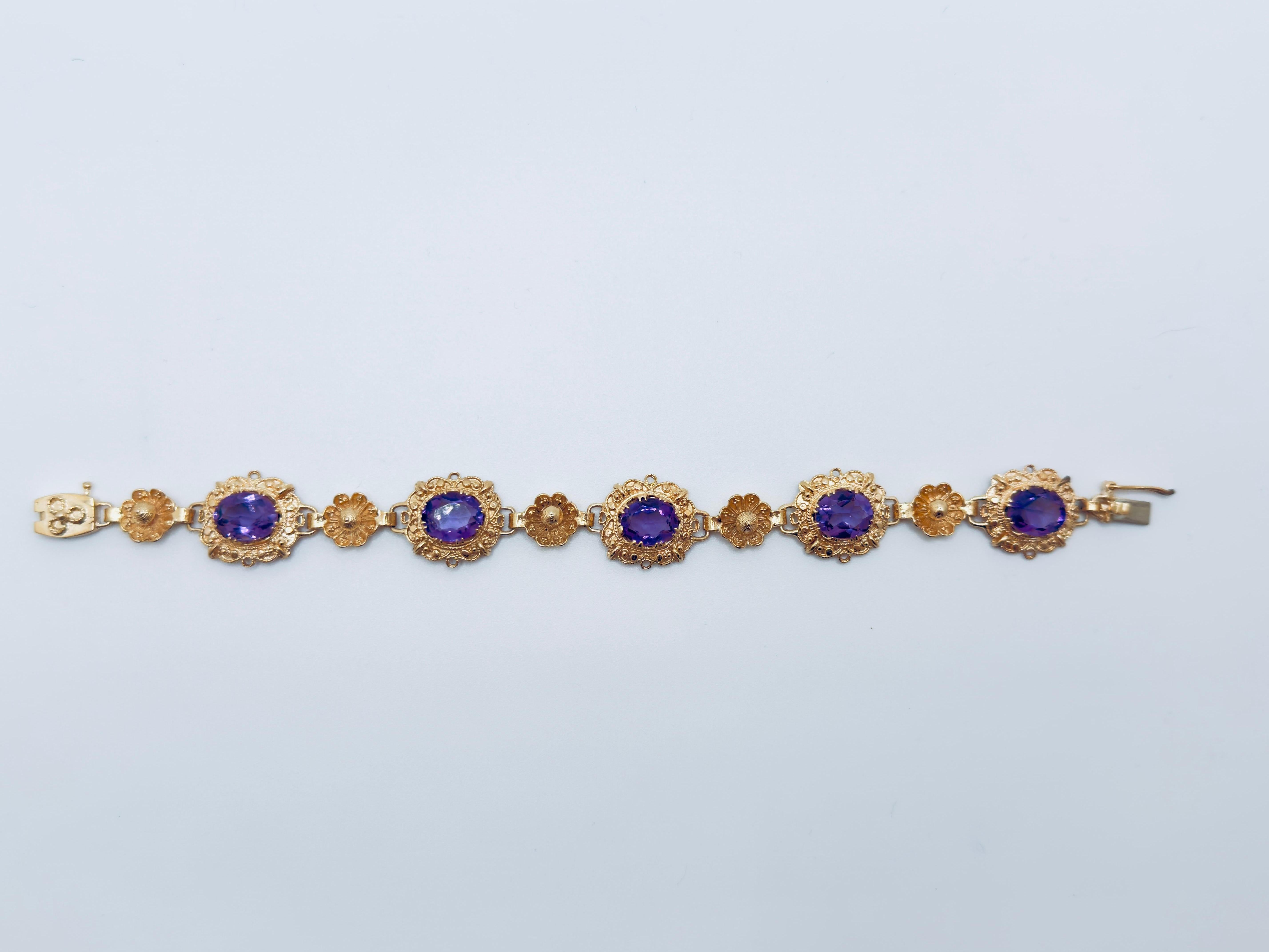 Esta llamativa pulsera de oro de 14 quilates presenta un diseño clásico centrado en cinco piedras ovales de amatista, cada una de las cuales mide aproximadamente 10x6 mm. Las gemas muestran un rico y vibrante tono morado, añadiendo un atrevido toque