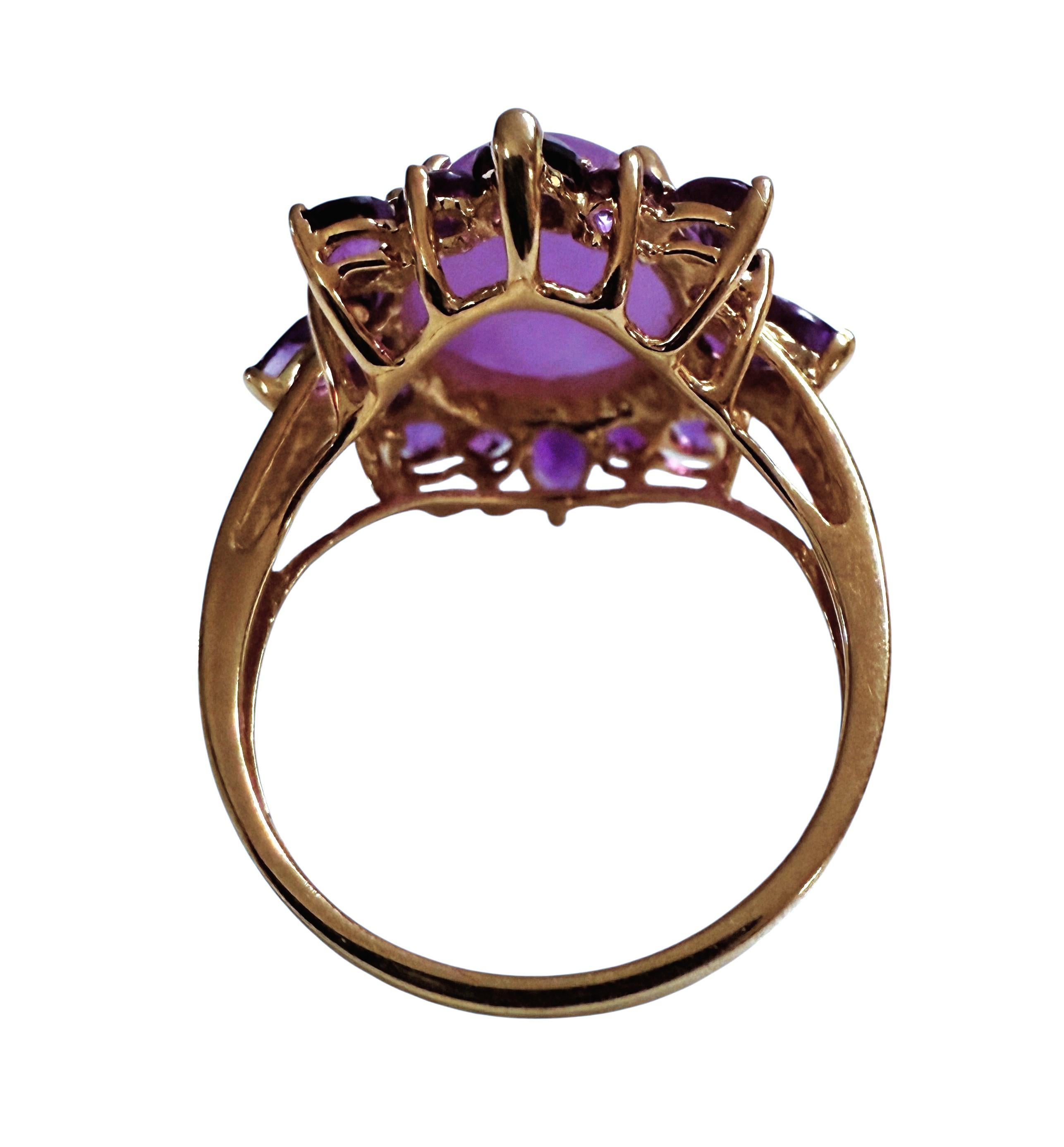 Questo anello è semplicemente uno spettacolo!   È un prodotto usato e in ottime condizioni.  Ha una pietra centrale di ametista cabochon da 3 carati ed è circondata da ametiste con taglio a pera e rotondo. È incastonato in una splendida montatura in