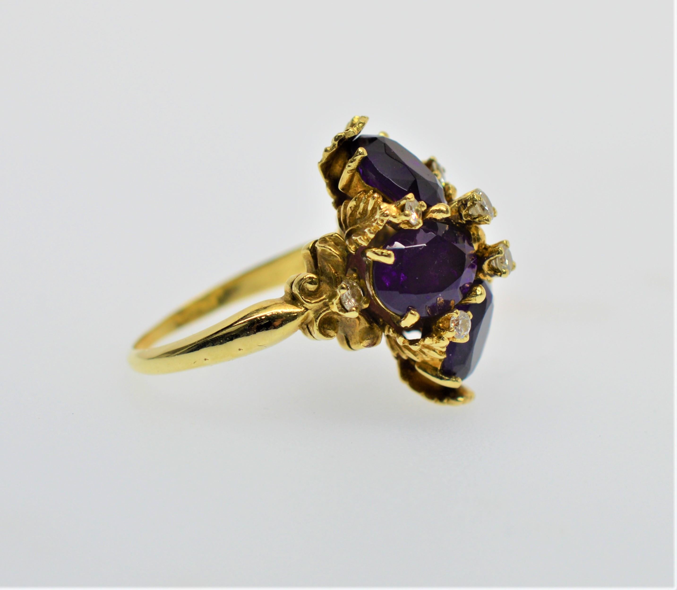 Four fabulous large faucet-cut oval genuine amethyst stones dressed with eight .01 carat diamonds present beautifully in this expertly crafted 14 karat yellow gold ladies cocktail ring. Bright 14 karat yellow gold leaves artfully frame the four deep