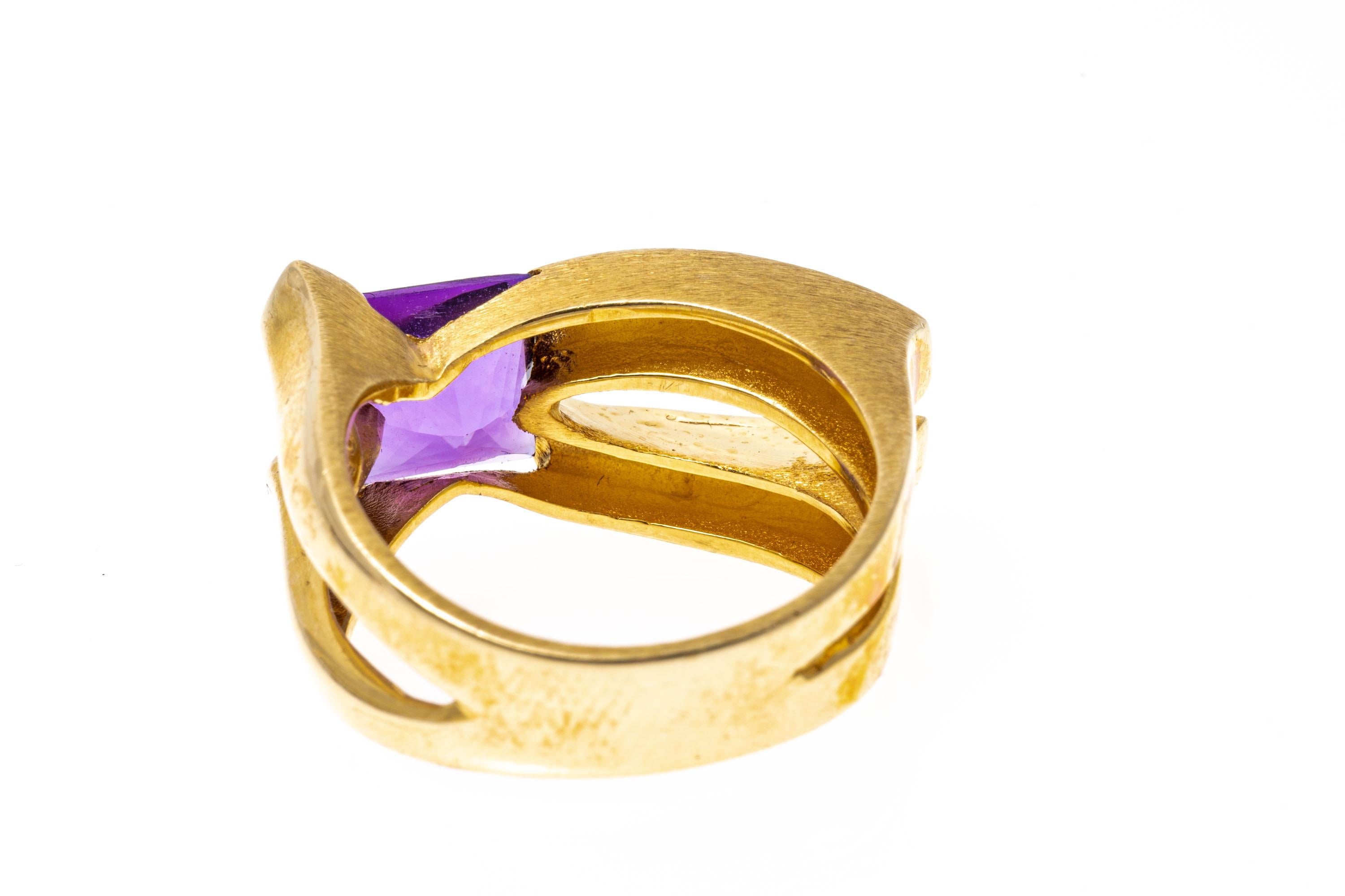 14k yellow gold ring. This unusual ring has a square, half-faceted, and half cabochon cut, medium to dark purple color amethyst, offset into a wide, elongated contemporary split, decorated with broad, split shoulders.
Marks: 14k
Dimensions: 15/16