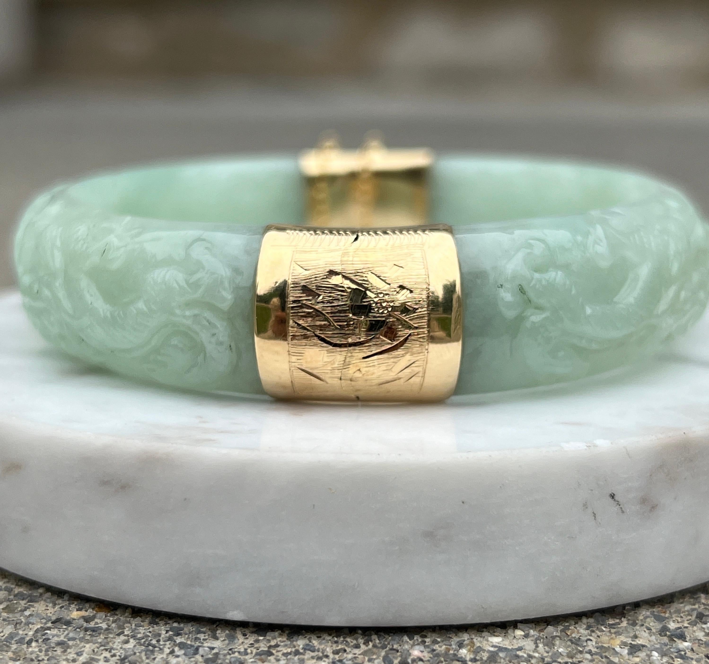 One light green carved jadeite bangle complete with 14 karat yellow gold button hidden tongue clasp and 2
