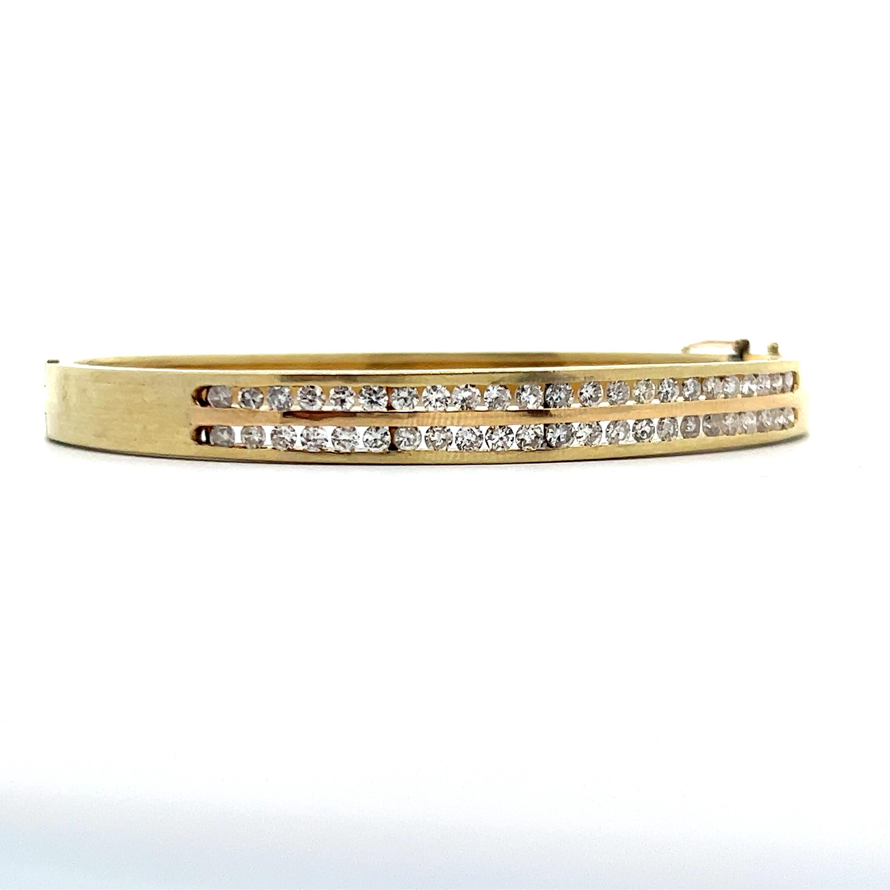 This is a beautiful 14k yellow gold bangle bracelet with two rows of diamonds. This bracelet features a unique design with the two rows of diamonds being channel set and only on one side of the bracelet. This design helps protect the the diamonds by