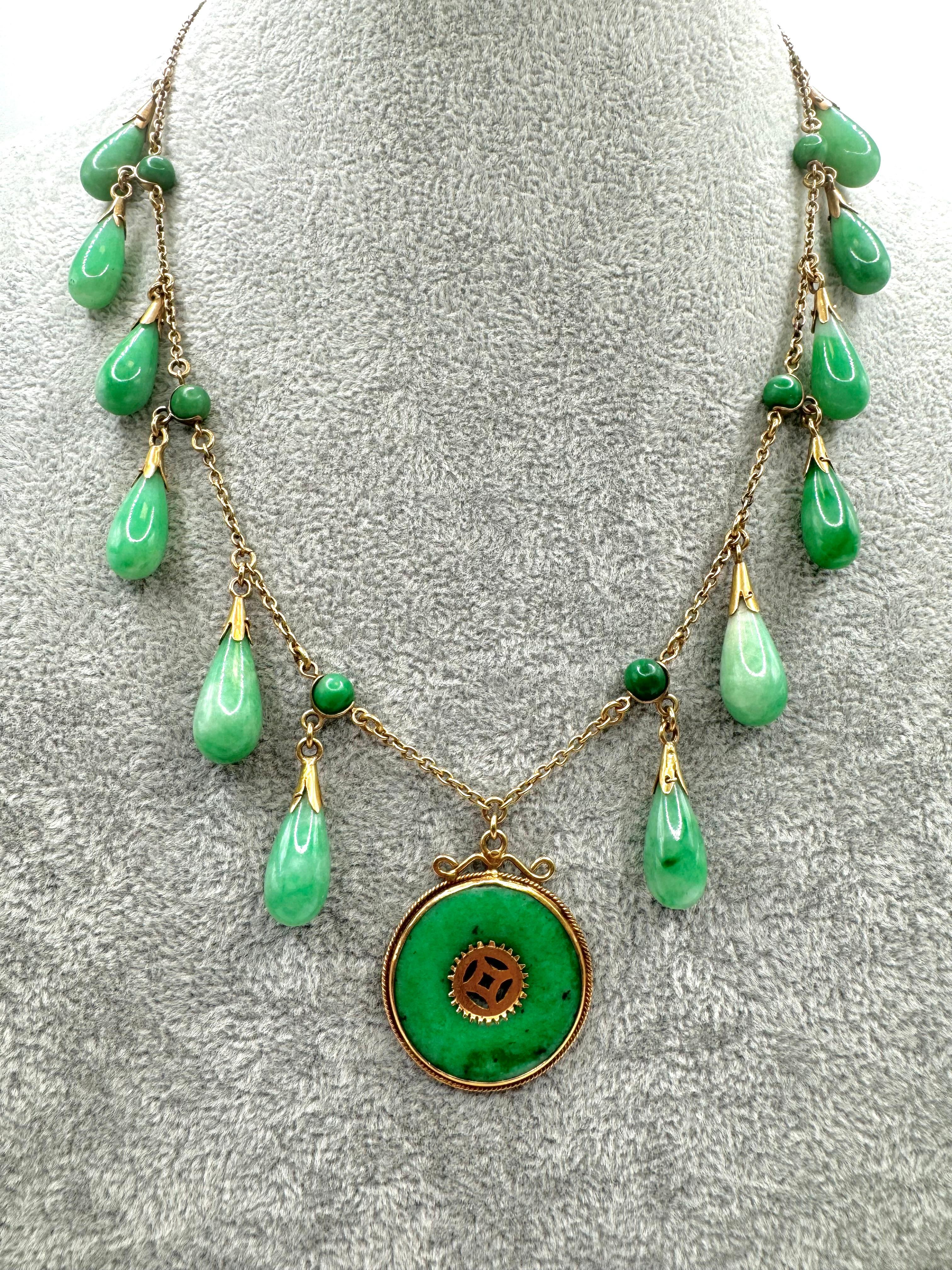 This elegant necklace showcases a striking blend of Art Deco influence and traditional Chinese design. Crafted in 14k yellow gold, the necklace features alternating carved jade beads and glossy jade teardrop pendants that cascade gracefully from a