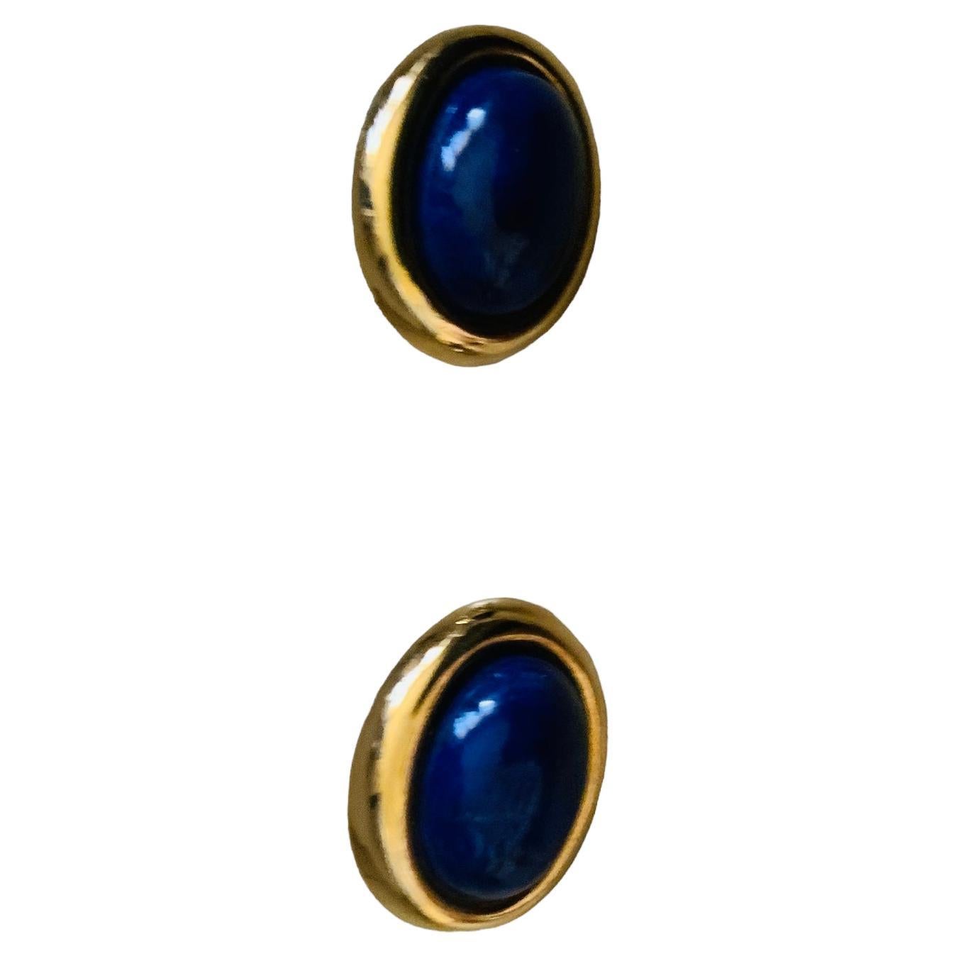This is 14K Yellow Gold and Lapis lazuli Pair of Earrings. It depicts an oval shaped cabochon Lapis lazuli stones mounted in a 14K gold bezel setting oval halo. They are hallmarked 14k in the back.