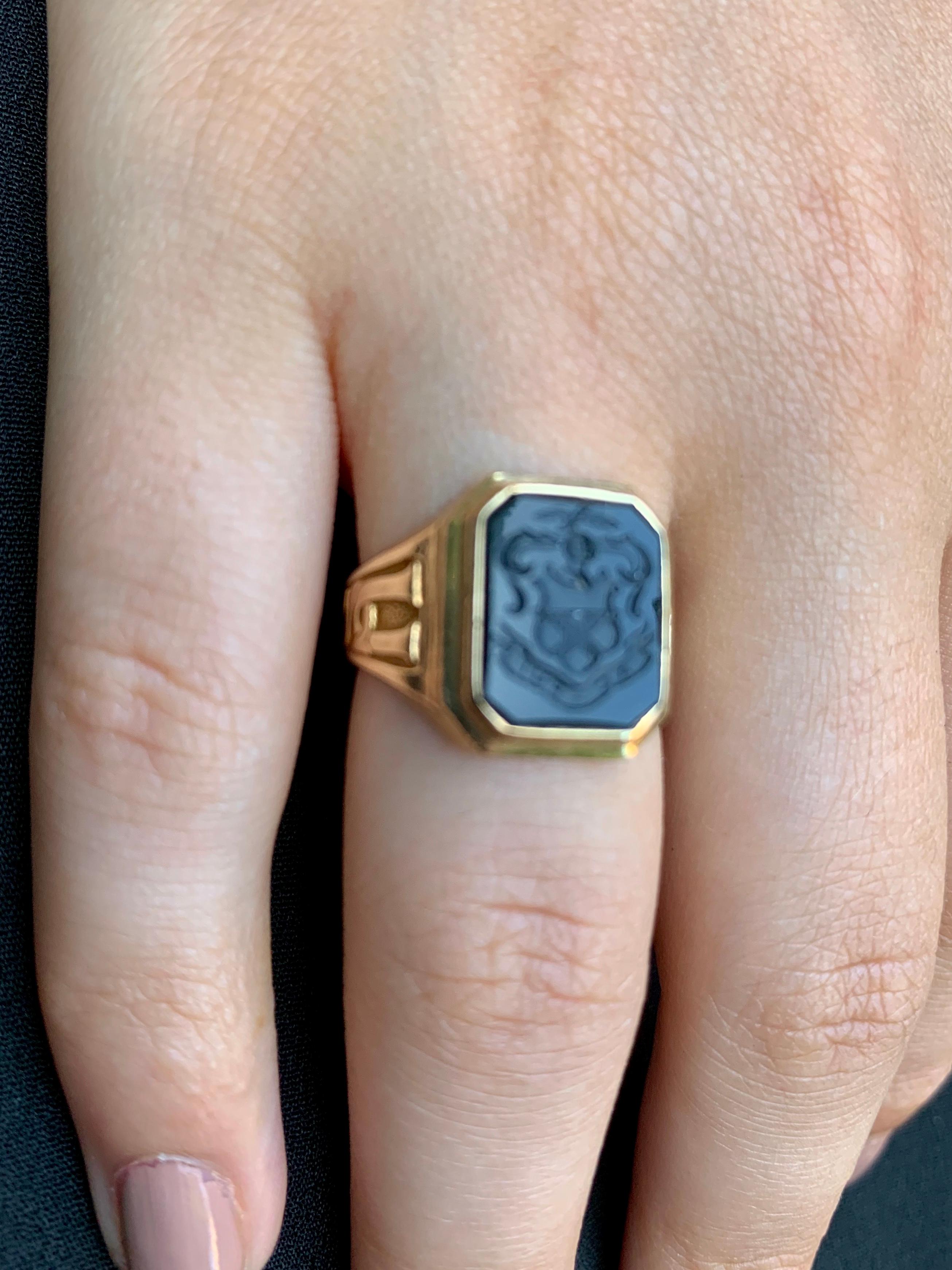 Fine Georgian style onyx intaglio ring engraved with an armorial heraldic device of a shield shaped crest topped with medieval style knight's helmet surrounded by scrolls and a central winged eagle, the base of intaglio with a banner and inscription