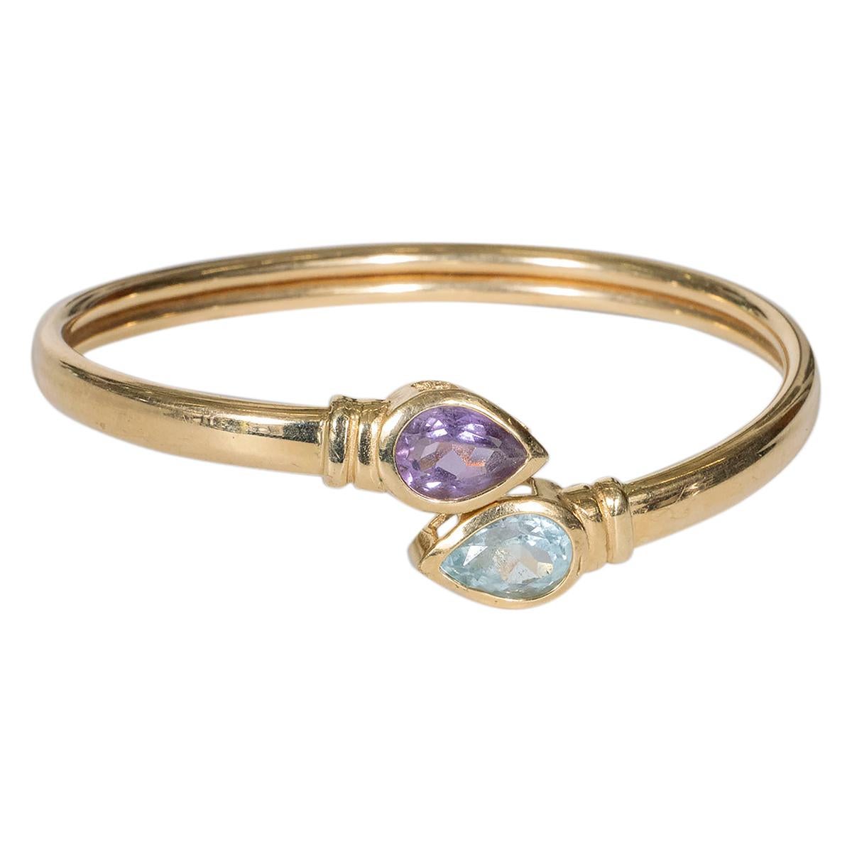 14K yellow gold open bangle bracelet with teardrop-cut amethyst and a aquamarine terminals. Interior bears designer double circle and arrow maker's mark. Interior measurements 2-1/8