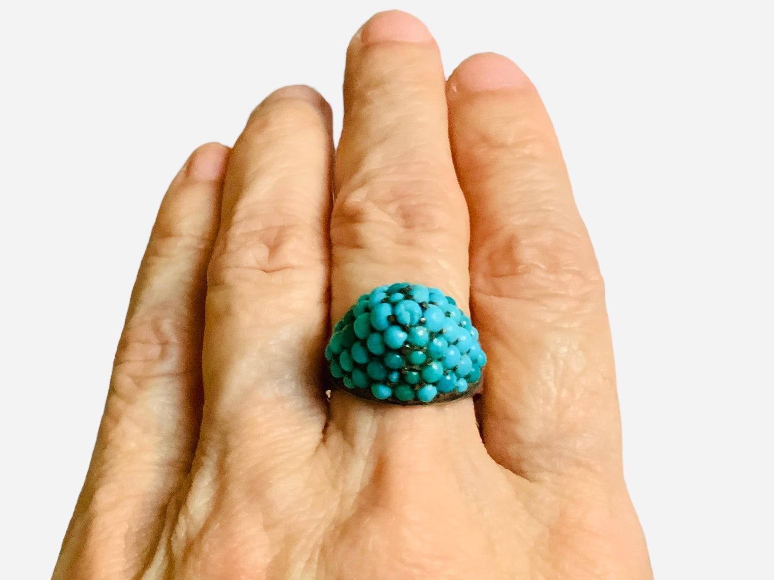 This is a 14K Yellow Gold and Turquoise Ring. It depicts a ring with multiple turquoise beads in prong setting adorning a piramidal dome. It is hallmarked 14 in one of its shanks.