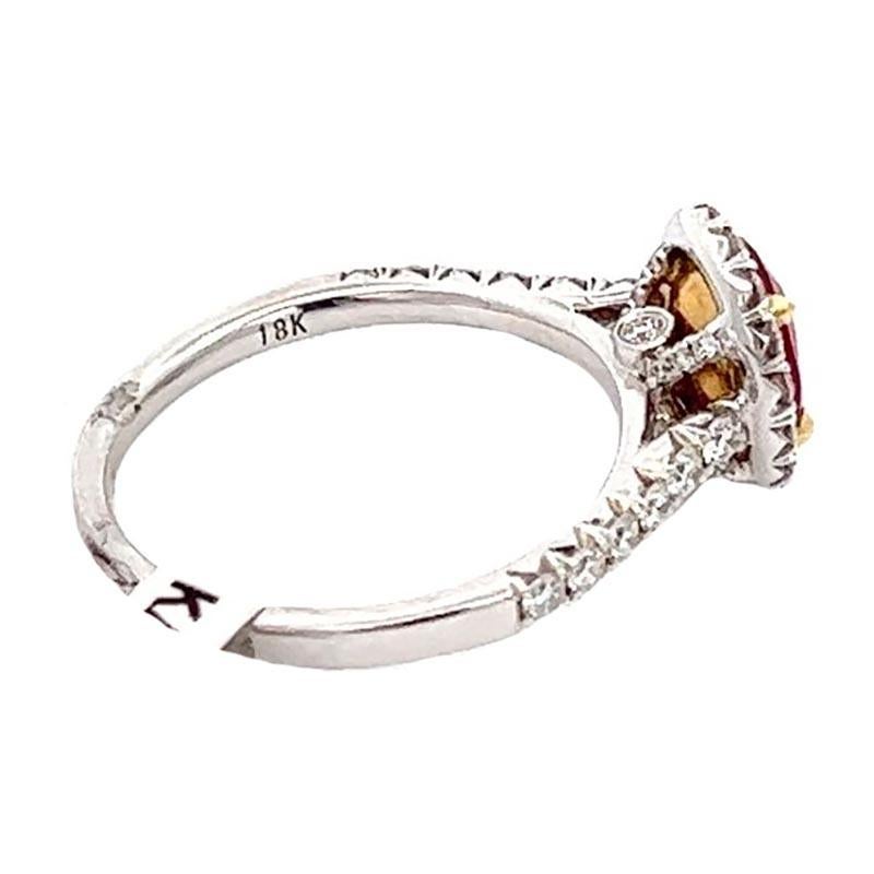 1.17 carat oval ruby and diamond cocktail ring featuring a vibrant red center stone. The 1.17 carat oval-shaped ruby is crafted in an elegant style mounting surrounded by a halo of pavé-set round brilliant diamonds in 14k white gold with an 18k