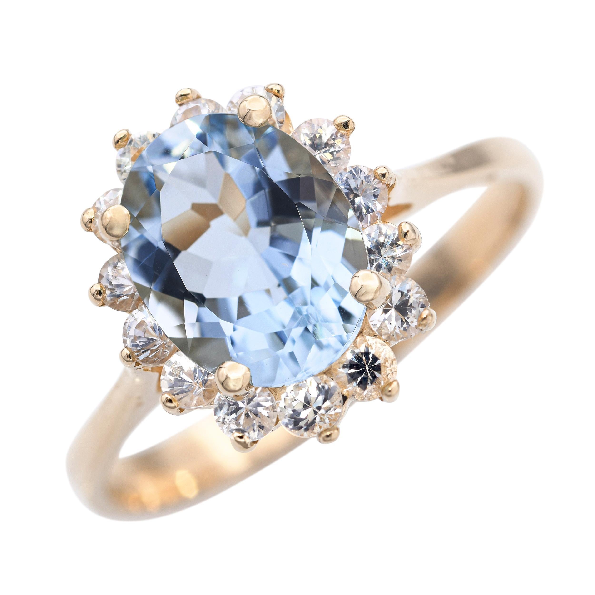 Cette bague présente une aigue-marine sereine sertie dans un riche or jaune 14k, entourée d'un halo étincelant de diamants. L'aigue-marine bleu pâle, connue pour son énergie apaisante et stimulante, contraste magnifiquement avec la chaleur de l'or