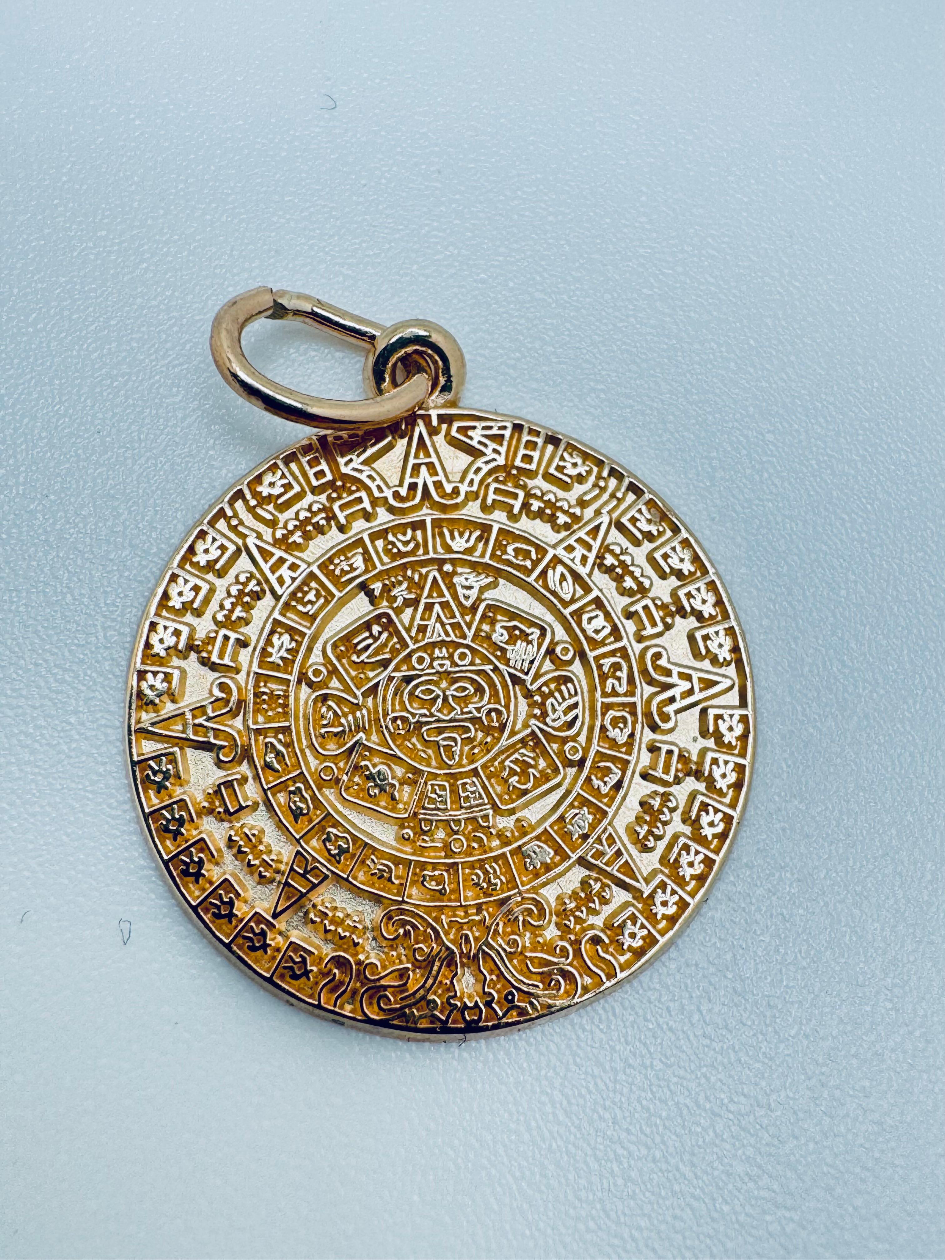 Ce pendentif à breloque Calendrier aztèque est un bijou symbolique de belle facture, réalisé en or jaune 14K poli et pesant 3,1 grammes. Mesurant 19,2 mm de diamètre et 1,04 mm d'épaisseur, elle offre une présence compacte mais substantielle qui la