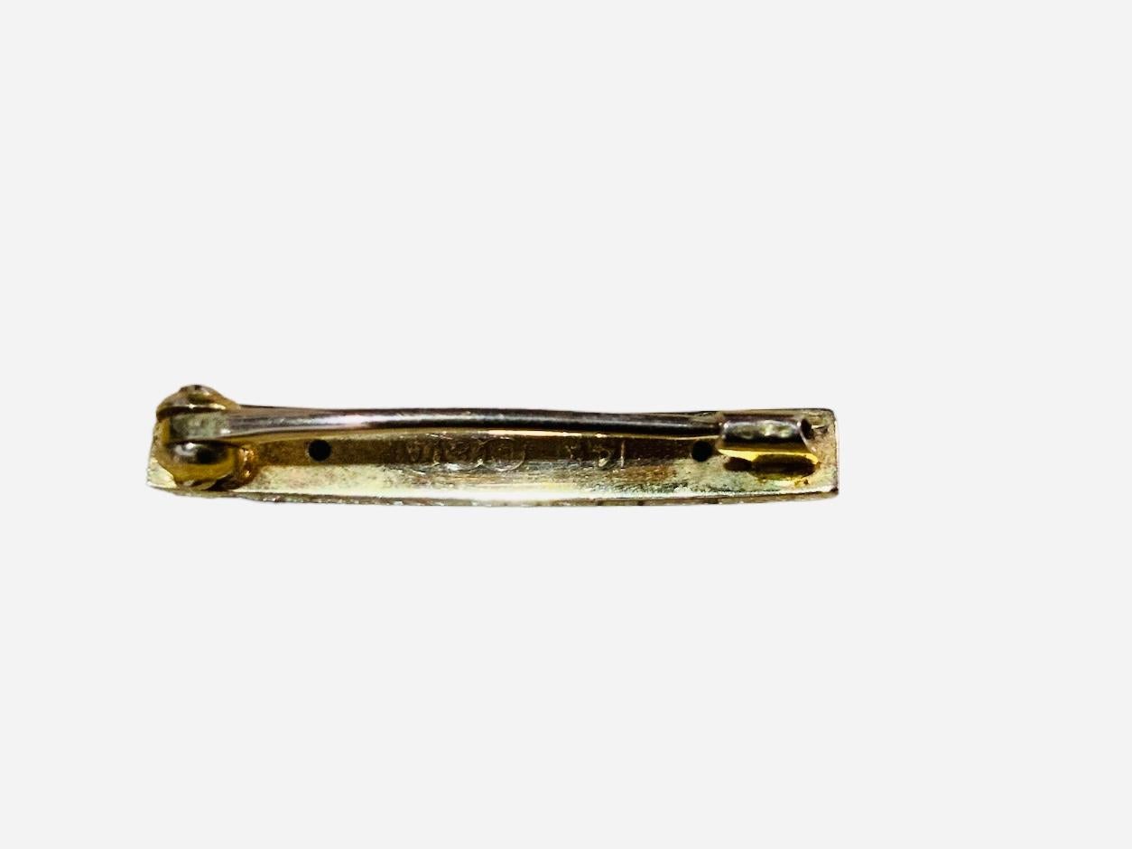 This is a 14K yellow gold “L&A” baby bar pin. It depicts an engraved with a flower and scrolls of acanthus leaves bar pin. It is hallmarked 14K and “L&A” in the back. It has a clasp to close.