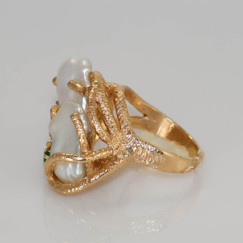 One 14k yellow gold freeform baroque freshwater pearl ring.
There are two pearls one overlapping the other.
They are set in a branch like design.
There are three small diamonds down the side, with one small emerald.
The size of  the ring  is 7