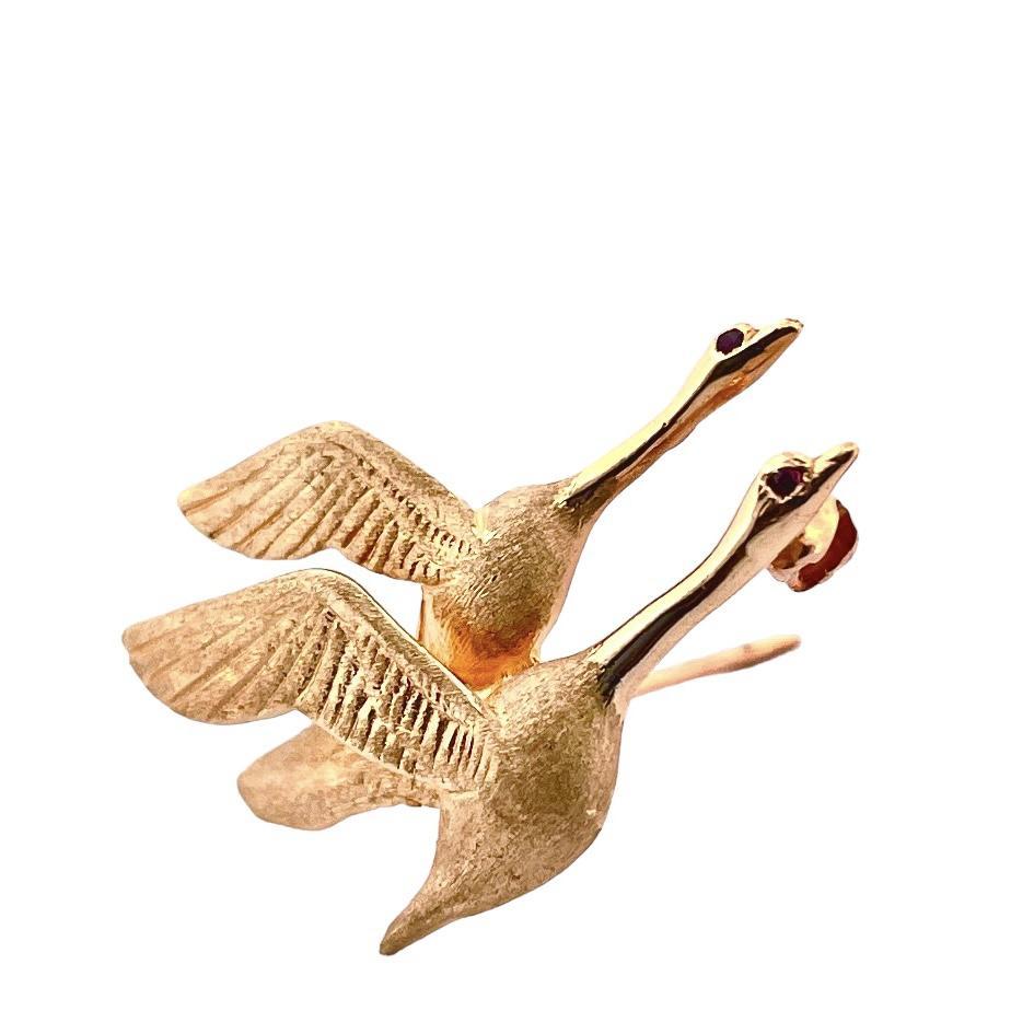 14K Yellow Gold Birds Flying Pin, where nature's grace and elegance meet the allure of rubies. 
This delicate pin, weighing just 4.2 grams, captures the essence of freedom and beauty with two intricately detailed birds in flight, 
each adorned with