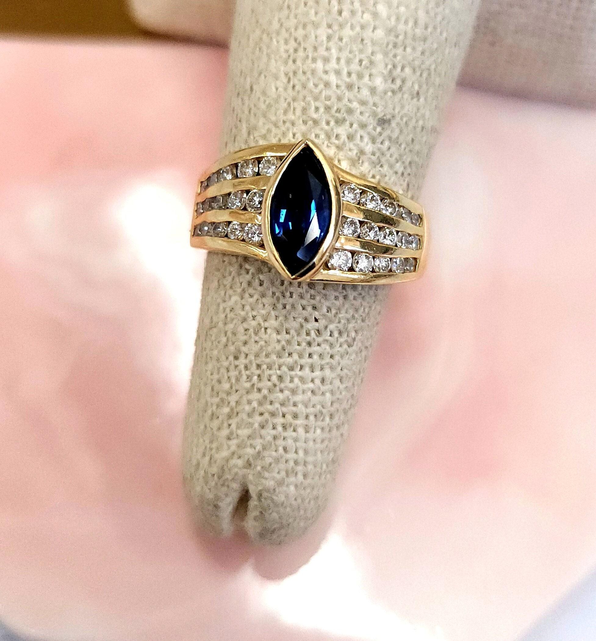 This is a vintage gold band featuring a marquise cut natural
blue sapphire with channel set diamonds set in a
Euro shank setting.

Details:
Blue sapphire measures 9.8 x 4.5mm sapphire ~1.25 carats
Bezel Set
Lovely deep blue tone.
~0.60 carats of