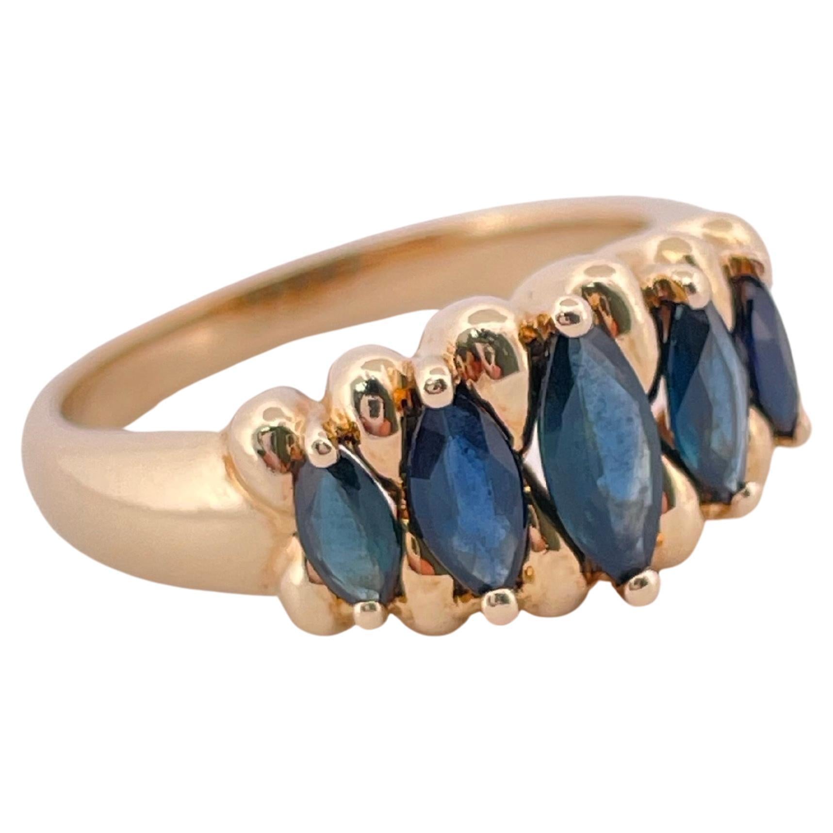 This elegant 14K yellow gold ring showcases a timeless row of deep blue marquise-cut sapphires, weighing approximately 5 grams in total. Each sapphire is expertly prong-set, allowing light to reflect across its faceted surface and enhance the