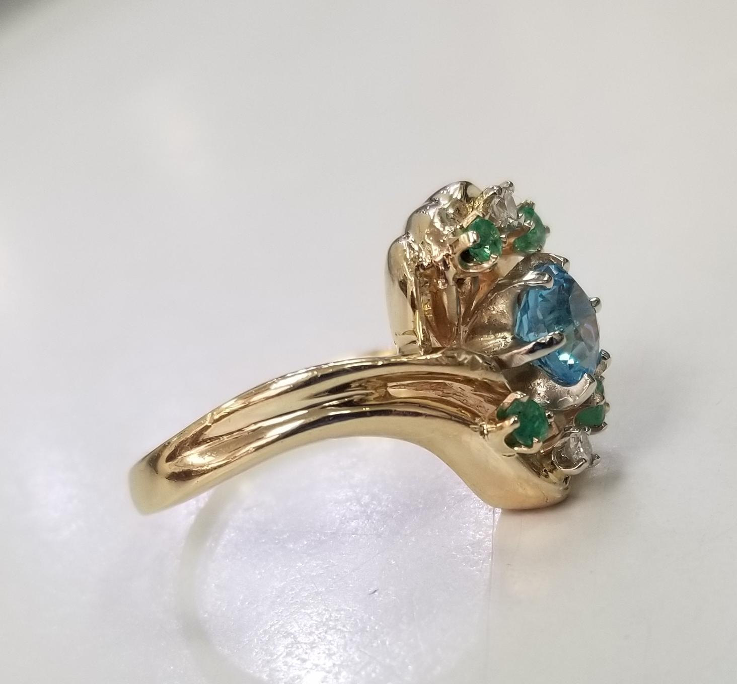 Specifications:
    main stone: 1 round Blue Topaz 1.00cts.
    other stones: 4 round emeralds .20pts.
    DIAMONDS: 2 round diamonds .05pts.
    color:GH
    clarity:VS2-SI1
    brand:-  metal:14K GOLD
    type: ring
    weight:7.6GrS
    size:8