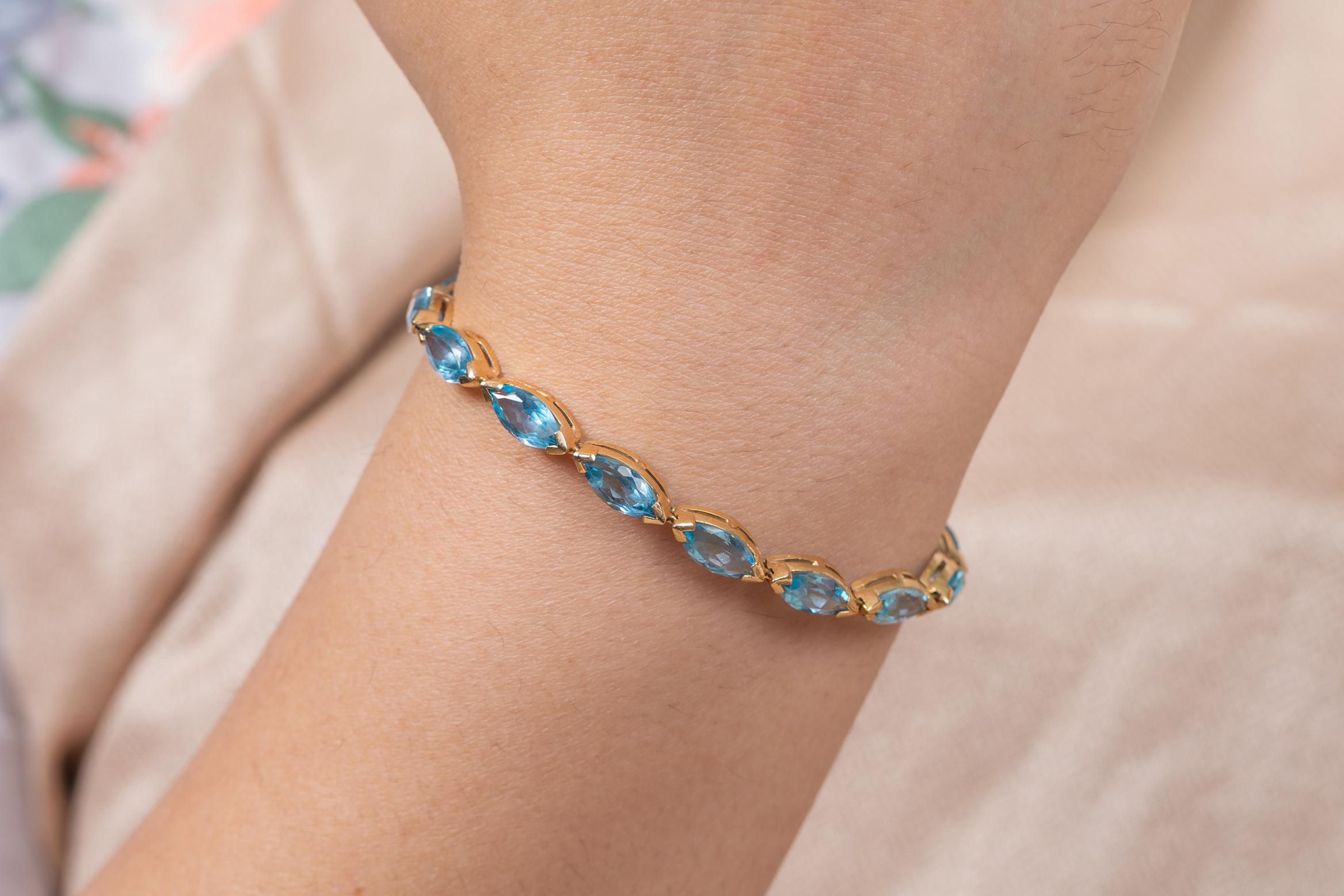 This Modern Marquise Blue Topaz Tennis Bracelet in 14K gold showcases 16 endlessly sparkling natural blue topaz, weighing 18.9 carats. It measures 8 inches long in length. 
Blue topaz helps to improve communication and self expression. 
Designed