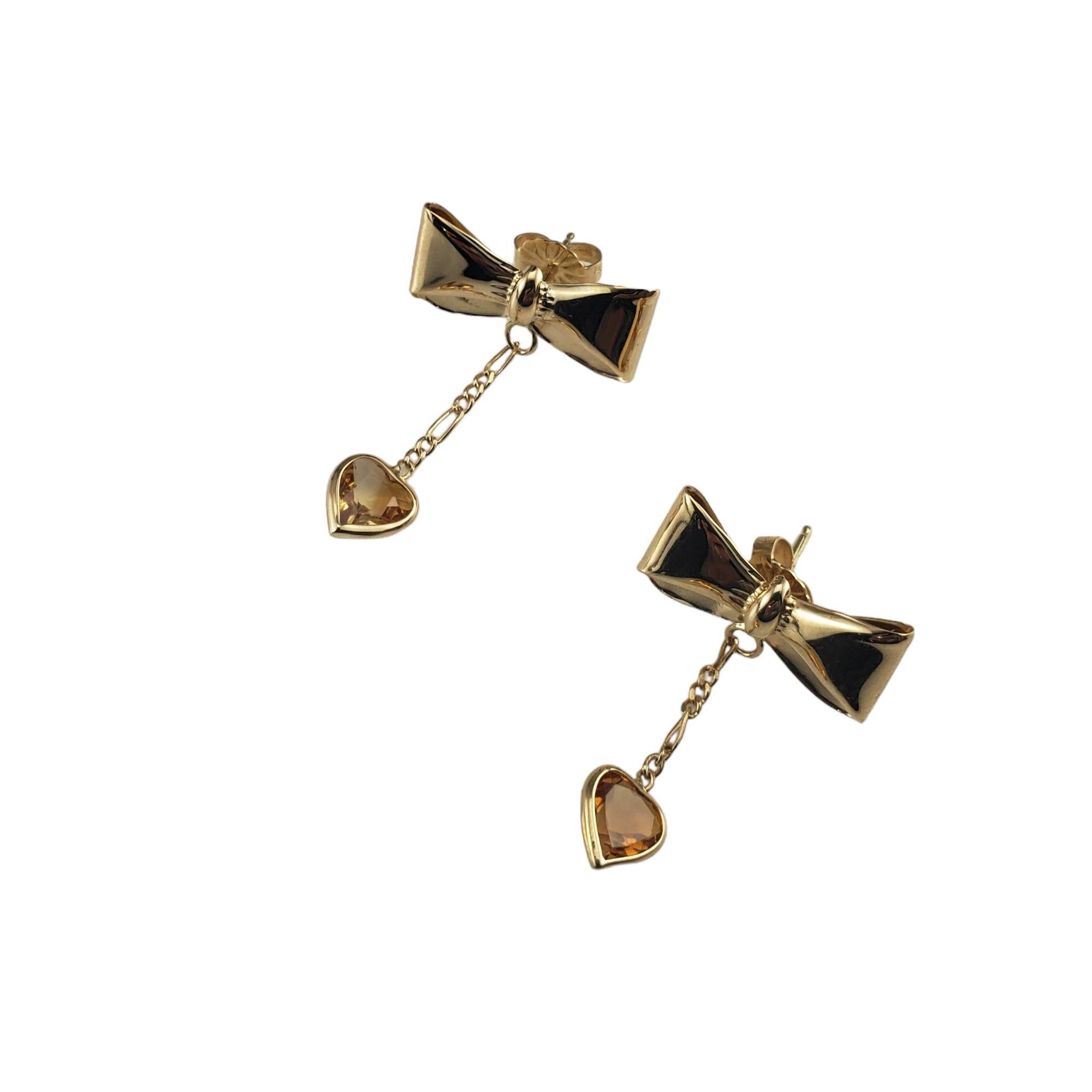 Vintage 14K Yellow Gold Bow Dangle Earrings-

These lovely bow earrings each features one dangling heart-shaped golden colored faceted stone.  Push back closures.

Size:  23 mm x 18 mm

Stamped: 14K

Weight: 1.2 dwt. / 1.9 gr.

Very good condition,