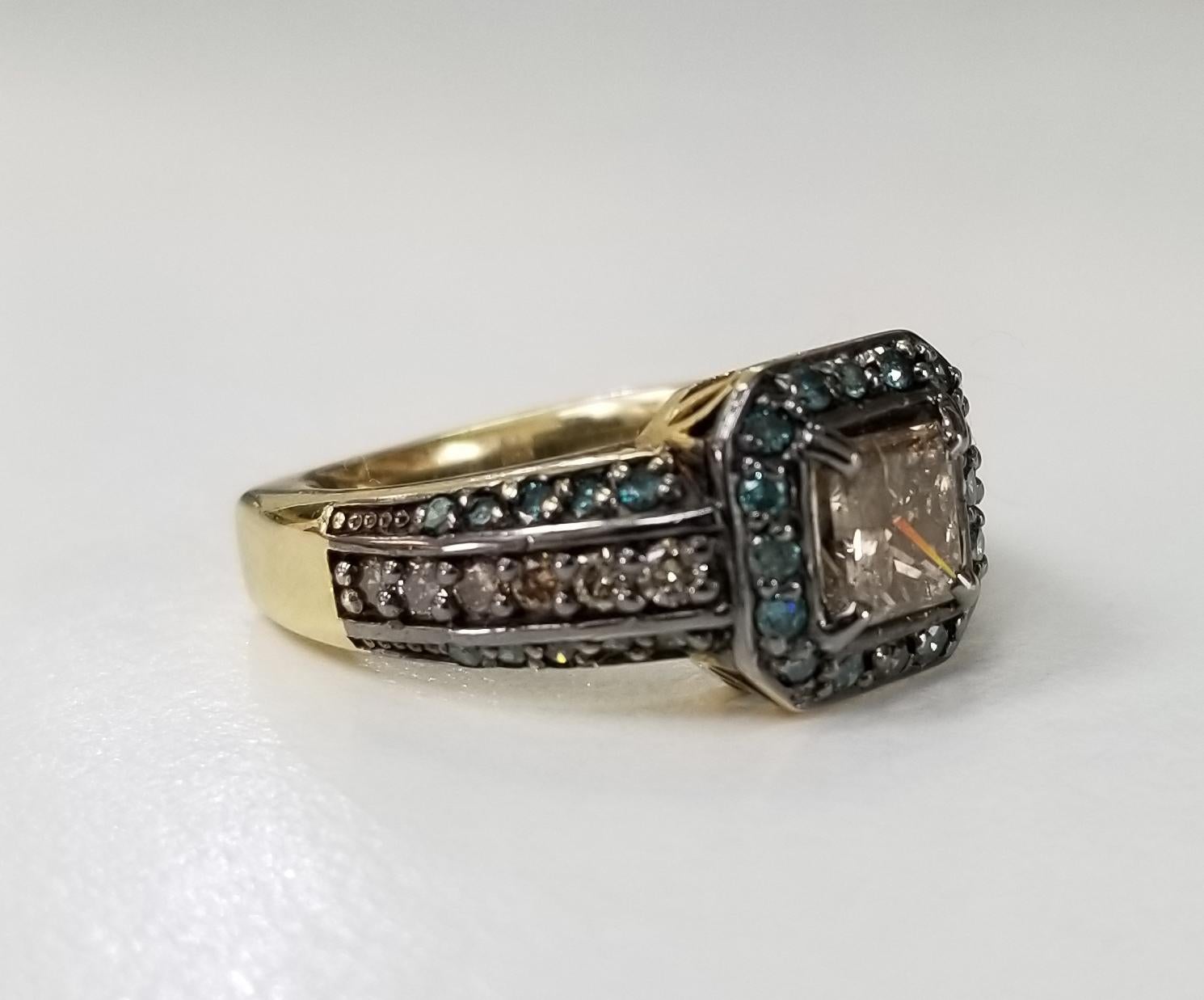 14k yellow gold brown and blue diamond halo ring containing 1 princess cut diamond weighing 1.00cts. also 12 round full cut brown diamonds weighing .30pts. and 36 round full cut blue diamonds weighing .50pts.   Top halo has been black rhodium.  This