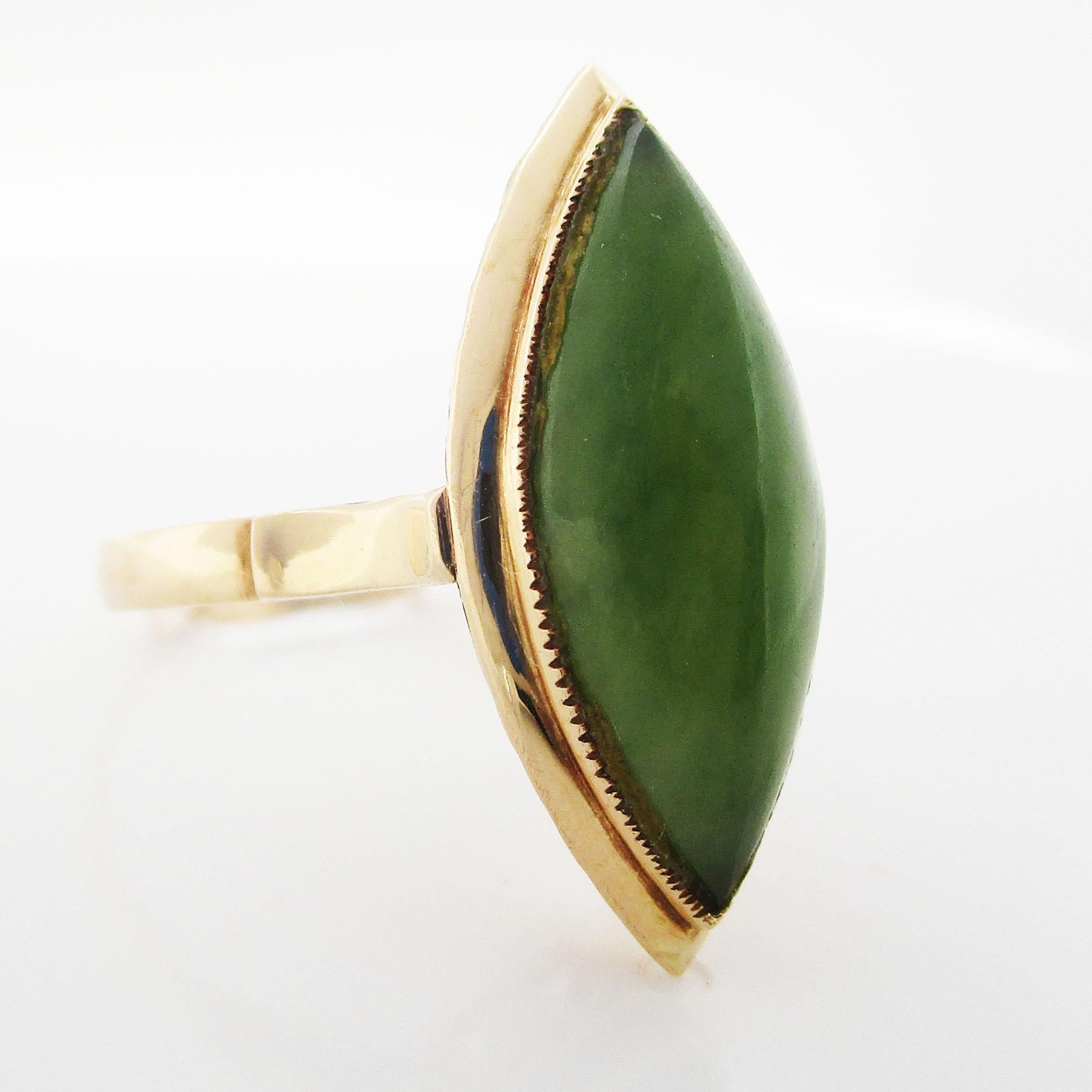 This is a captivating 14K Yellow Gold Ring, featuring an exquisite Nephrite Jade cabochon. 

The stone is an exceptional 21 mm x 9 mm. The under gallery is constructed with enchanting filigree detailing that allows light to come through the jade,