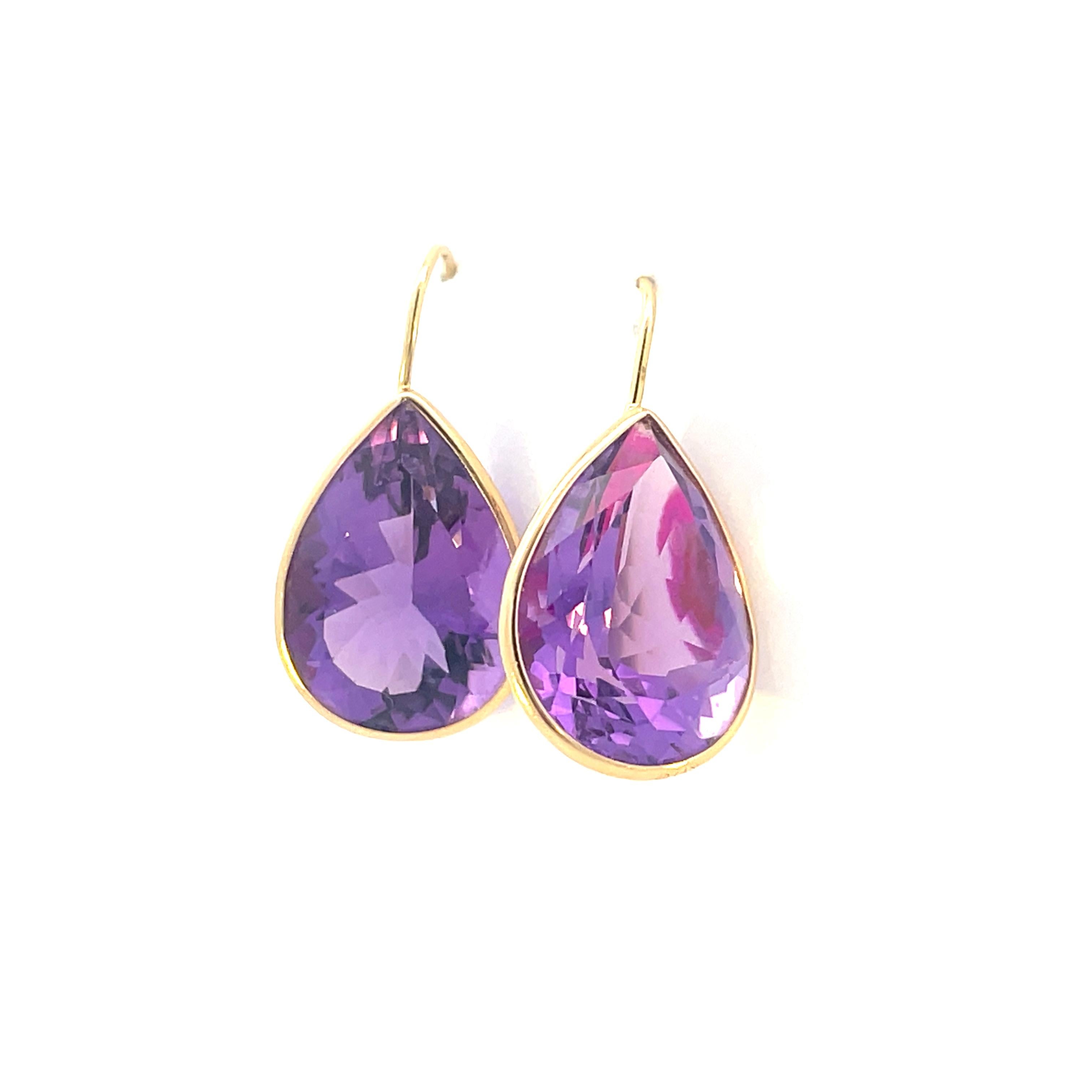 This stunning pair of 14k yellow gold earrings feature an almost invisible channel set purple teardrop shaped amethyst, each with an approximate carat weight of 10. The light lavender with subtle red finishes in the amethyst combined with the