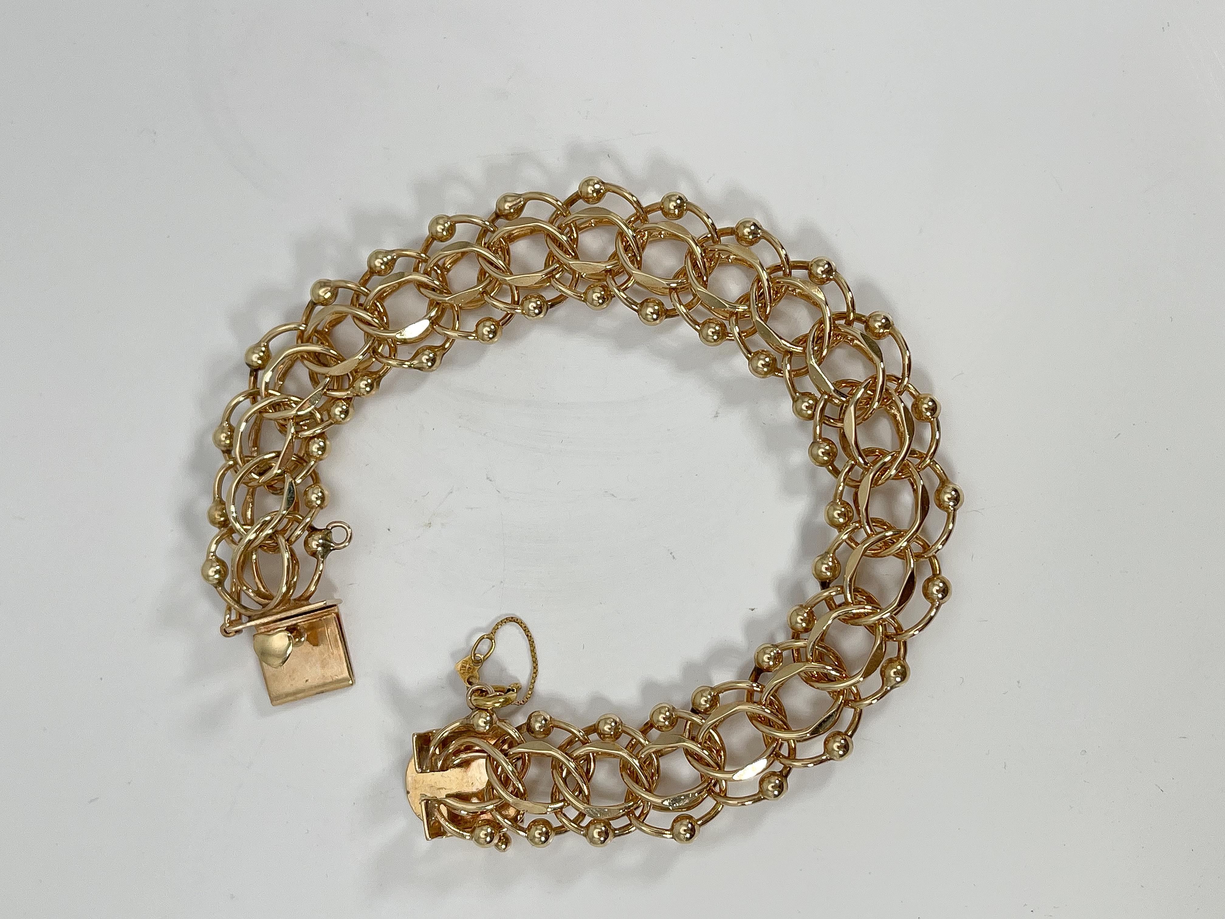 Bracelet à breloques en or jaune 14k. Ce bracelet est doté d'un fermoir en forme de 8 qui s'ouvre et se ferme et d'une chaîne de sécurité. La largeur est de 14,5 mm, la longueur de 7,5 pouces et le poids total de 30,08 grammes.