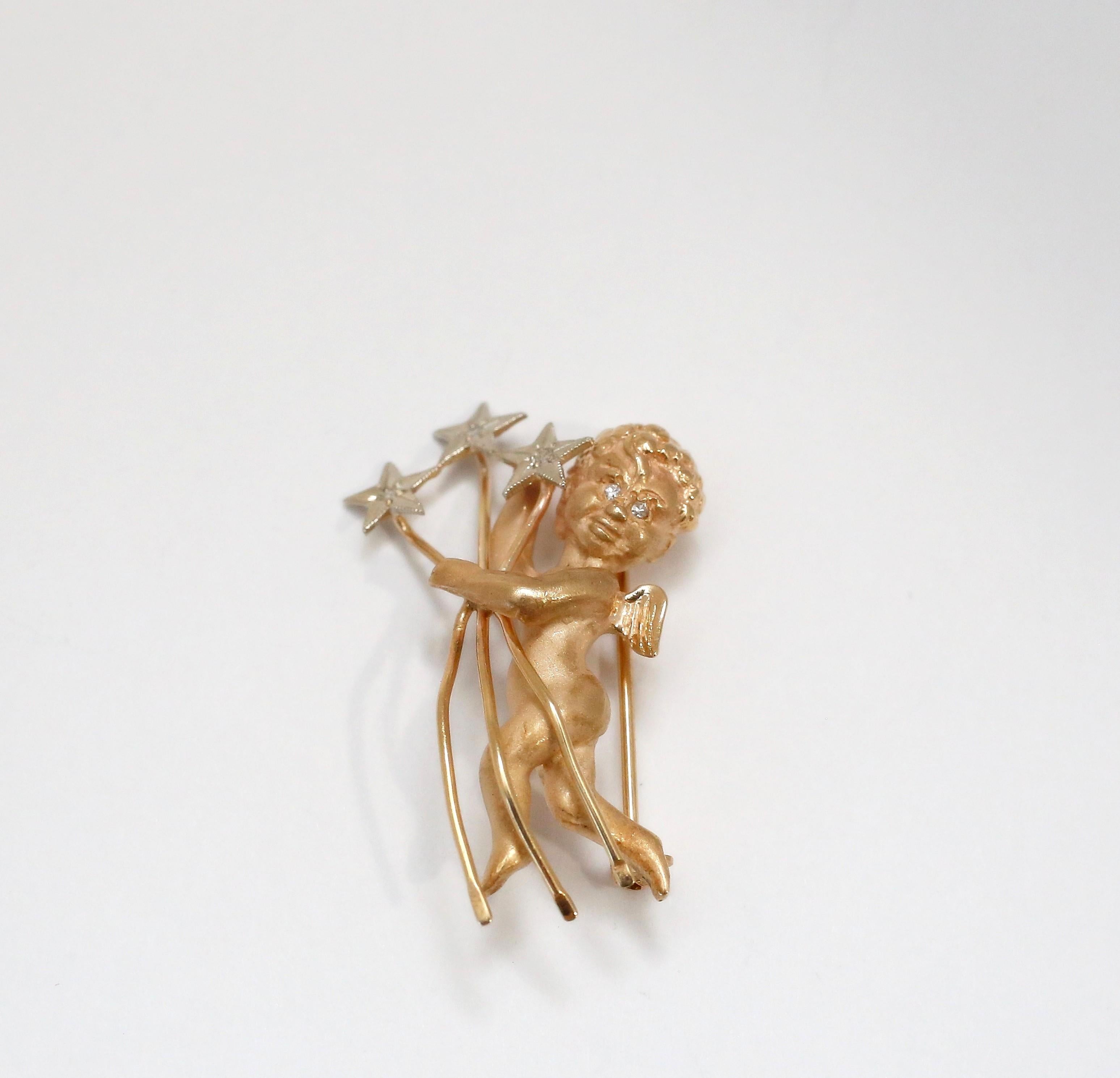 This enchanting 14k brooch features a beautifully detailed cherub in mid-flight, crafted in warm yellow gold. The cherub holds three white gold stars, each adorned with a sparkling diamond at its center, while two additional diamonds shimmer from