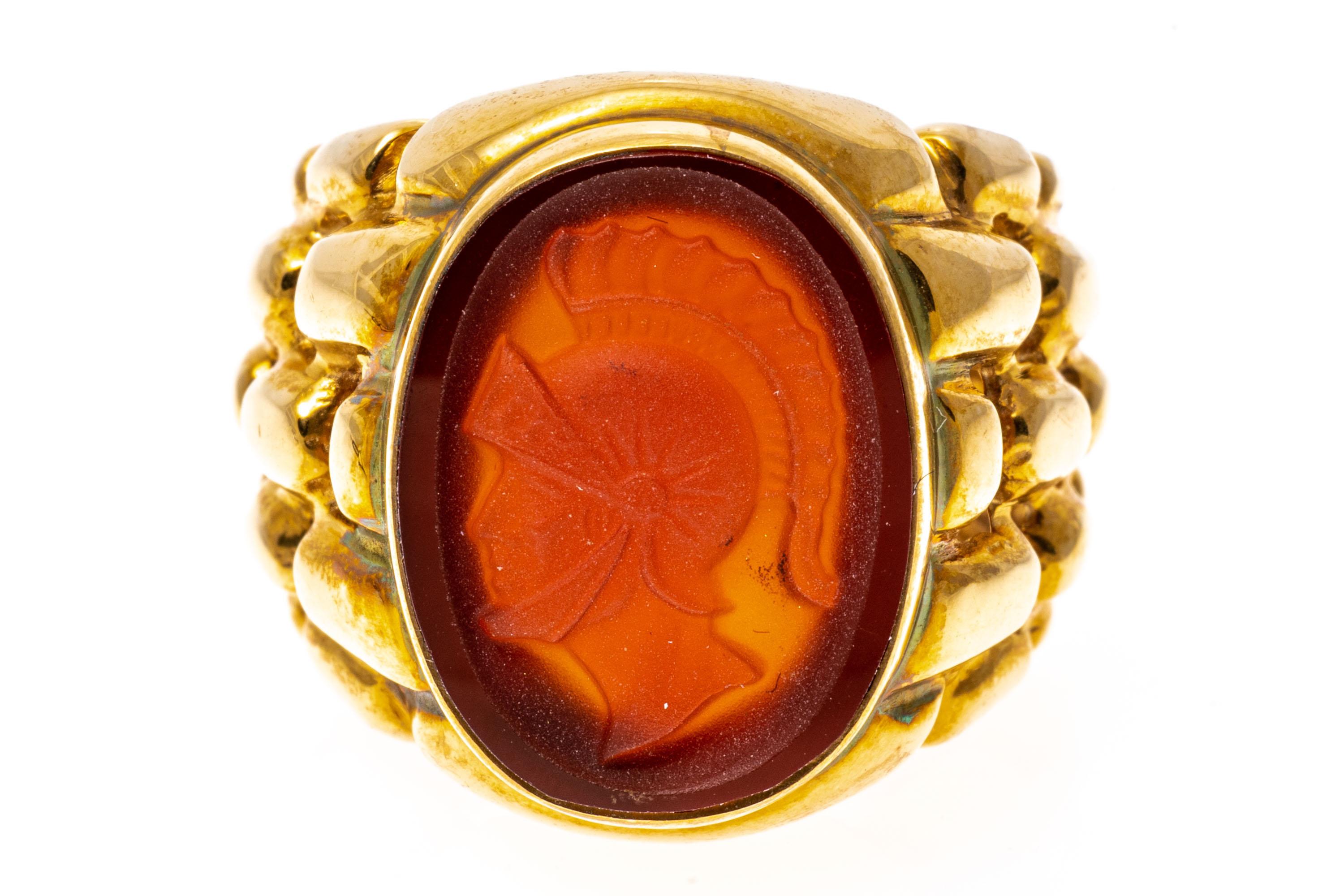 14k yellow gold ring. This gorgeous contemporary oval laser cut cameo ring has a dark orange carnelian background with a lighter orange foreground of a handsome bust of a soldier, facing to the left. The ring is also a signet profile, adorned with