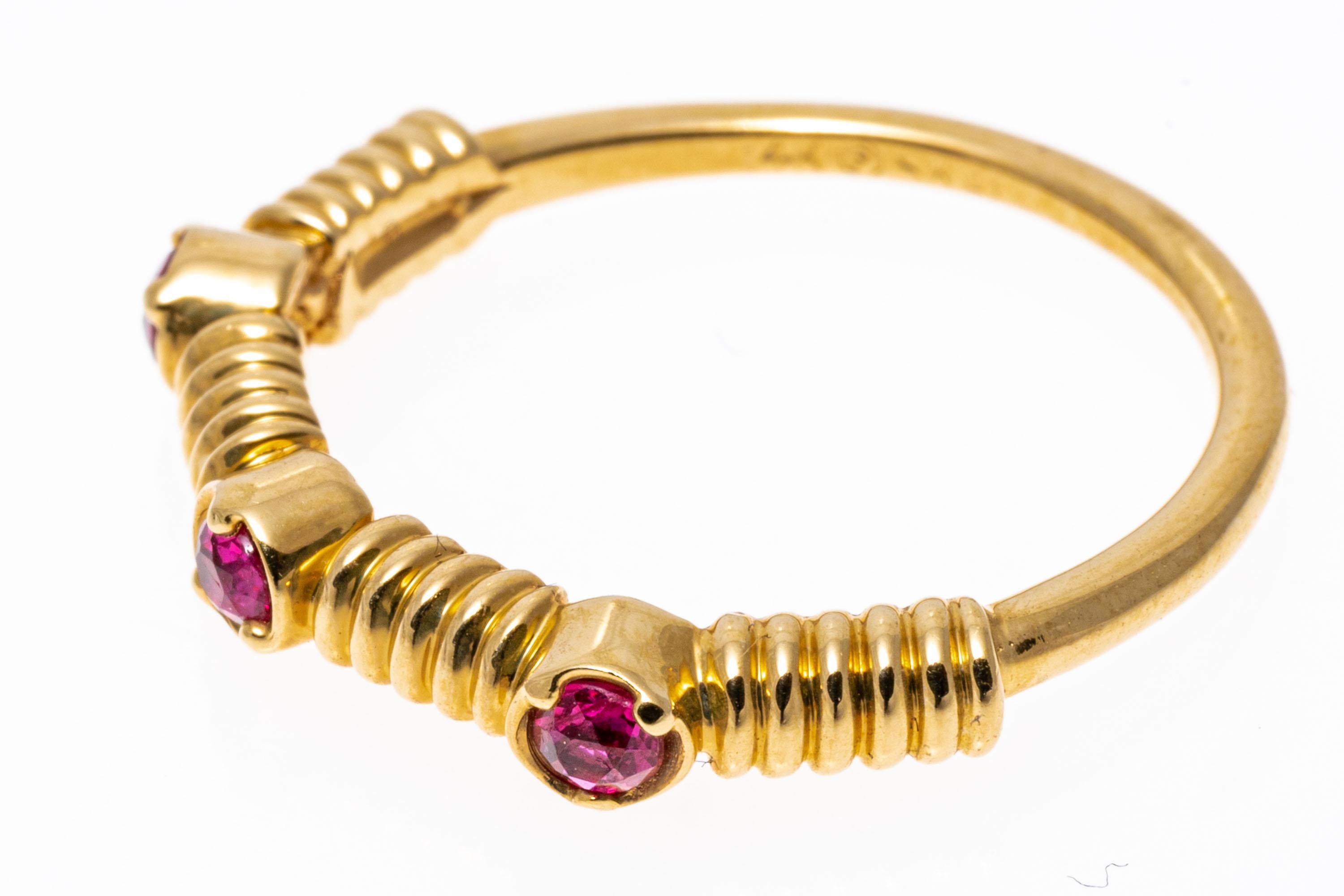 14k yellow gold ring. This fun ring is a contemporary ribbed band style ring, set with three round faceted, pinkish-red color rubies, approximately 0.27 TCW, prong set.
Marks: 14k 
Dimensions: 3/4
