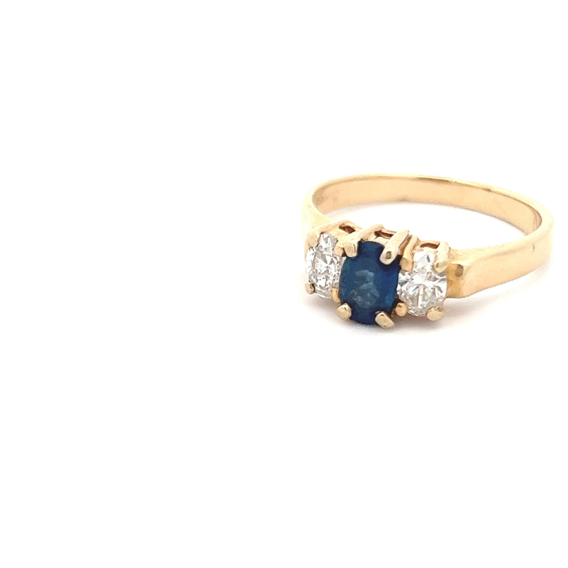 This 14k yellow gold contemporary ring is lovely, featuring both diamonds and sapphire. The ring showcases a 3 stone ring design with diamonds on the shoulders and a sapphire center stone. Though the design is traditional, the look is bold, as the