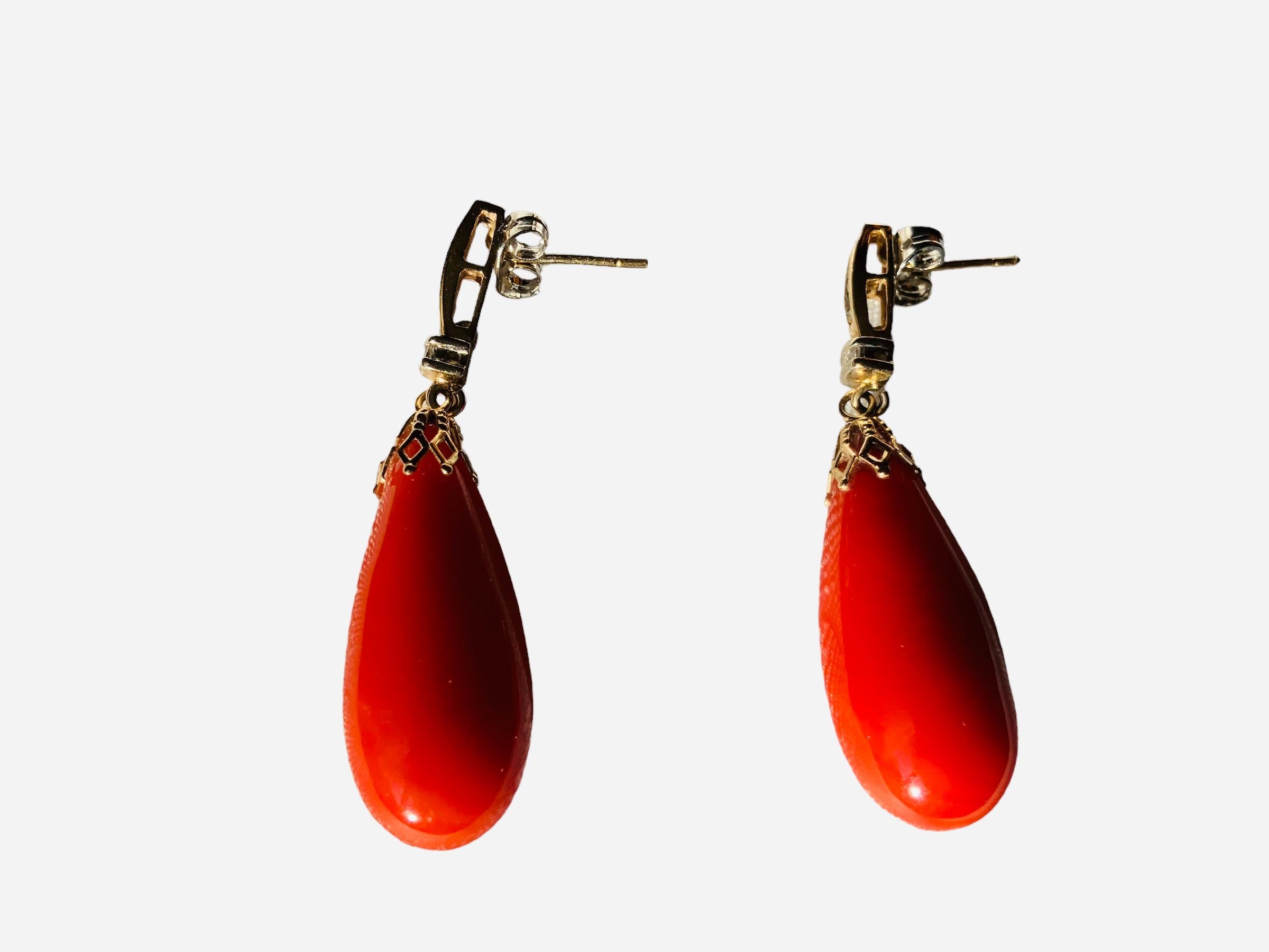 This is a Pair of 14K yellow gold Red Coral and Diamonds Drops Earrings. The coral is shaped as long tear drops mounted in 14K yellow gold with pression back. They contain 16 diamonds weighing 0.20 carats.