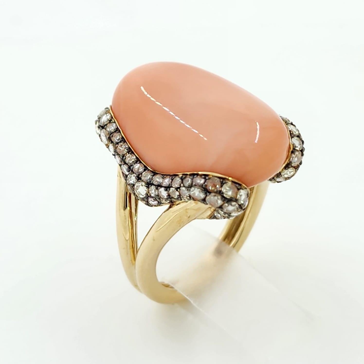 Make a bold and elegant statement with this sculptural ring showcasing a single 21.00 carat coral cabochon. The smooth, organic shape of the coral is embraced by a sinuous swirl of 122 rose-cut diamonds totaling 1.22 carats, carefully set to