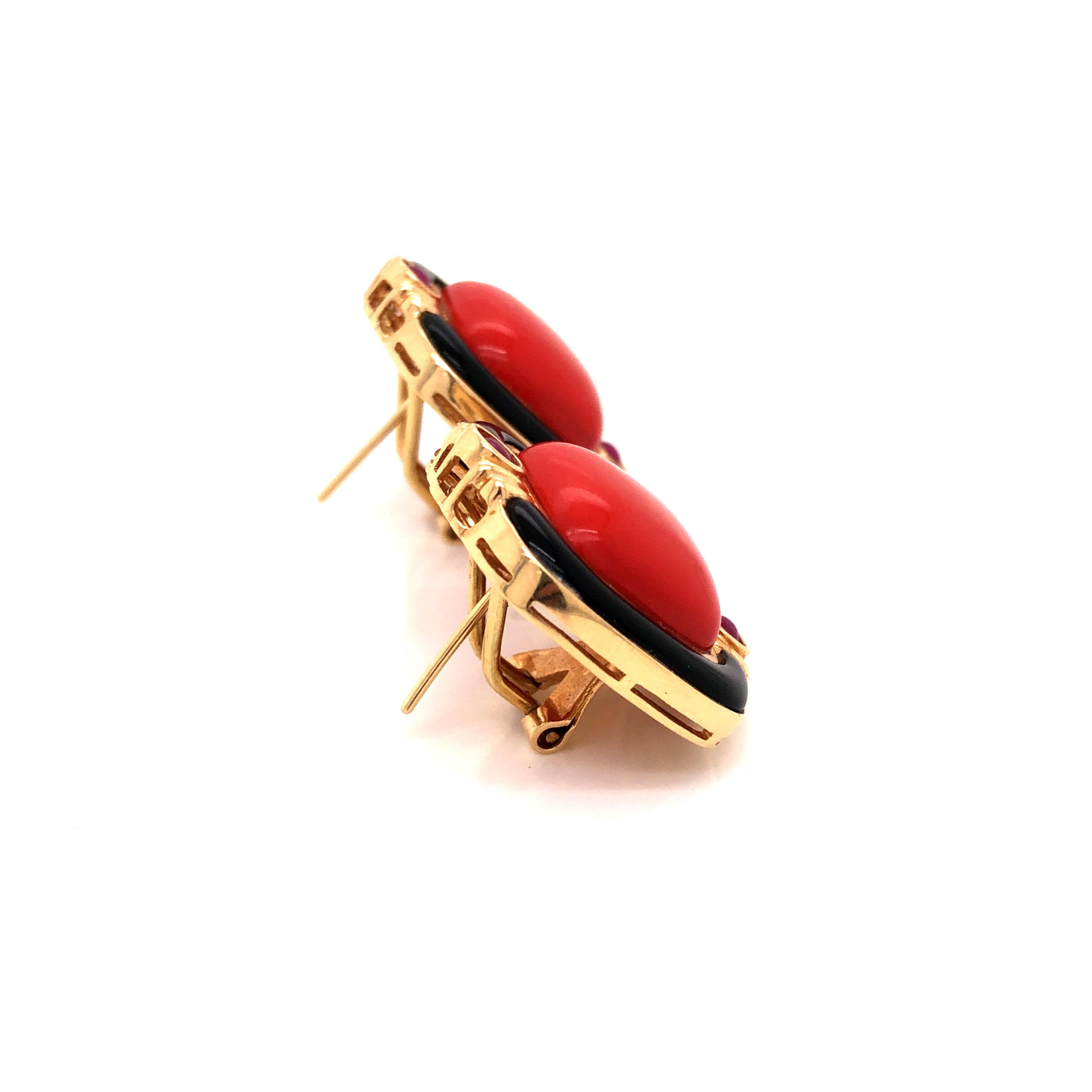 A pair of 14K yellow gold earrings featuring coral cabochons surrounded by polished onyx panels and round ruby cabochons.

Stone: Coral, Ruby

Metal: 14K Yellow Gold

Size: 7/8