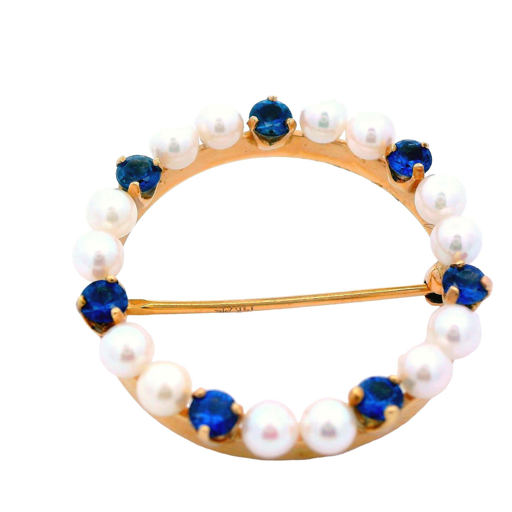 This beautiful Craig Drake royal blue natural pin is made in 14k yellow gold and features both sapphire and pearls. The pins circle design is indicative of the contemporary movement and allows the pin to better boast the white creamy pearls and rich