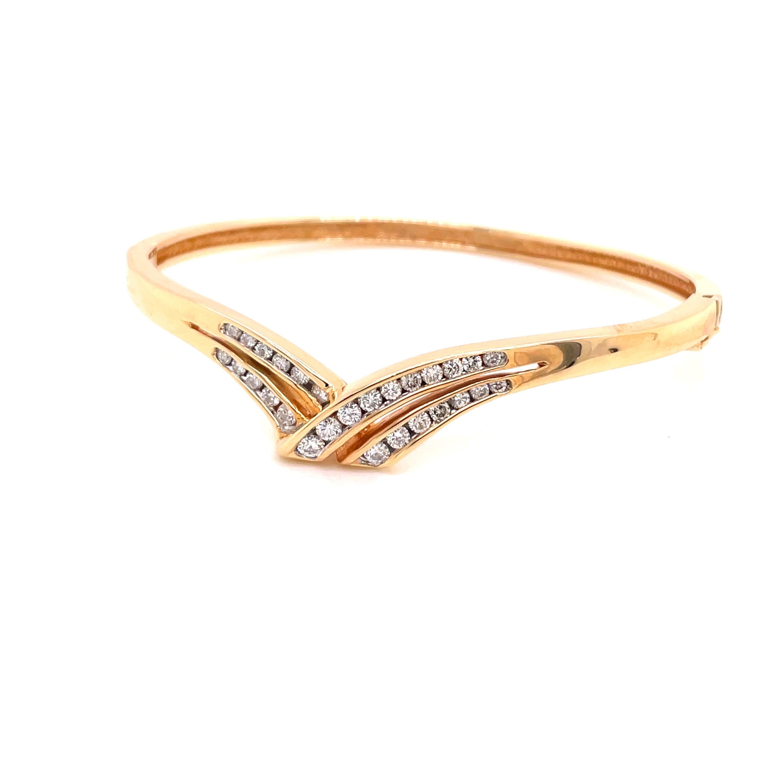 14K Yellow Gold Diamond Bangle Bracelet .87ct - The bangle has channel set 28 round brilliant diamonds weighing .87ct with G - H color and SI clarity. The width of the bangle on top is 8mm and tapers to 3.3mm on the bottom. The ribbon design extends