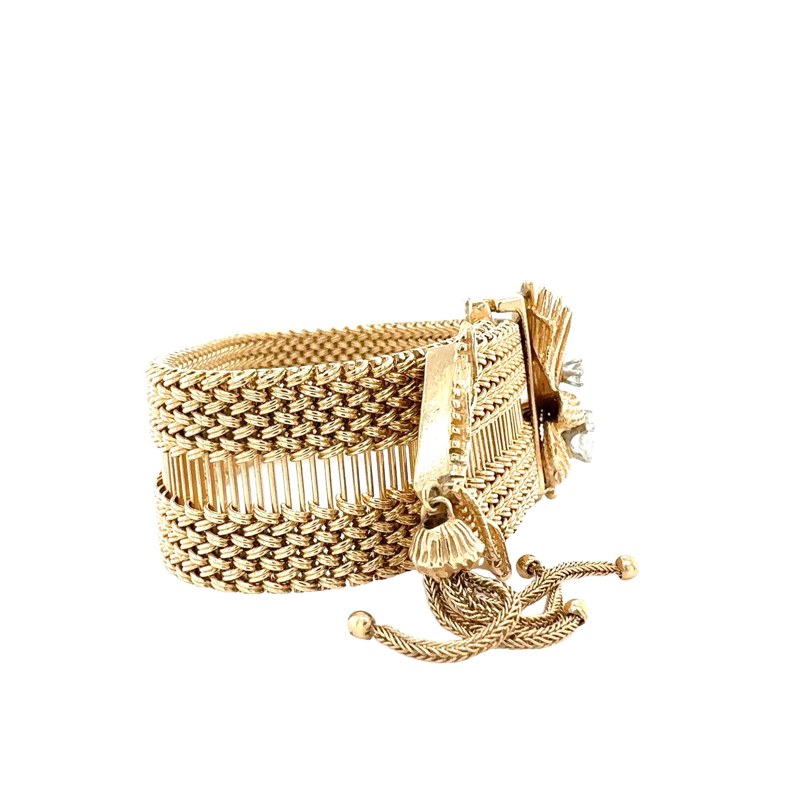 Esta exquisita pulsera con hebilla de oro amarillo de 14 quilates de la década de 1960 combina el encanto vintage con lujosos detalles, presentando un exclusivo motivo de abanico y un juguetón acento de borla dorada. En el centro, un hermoso