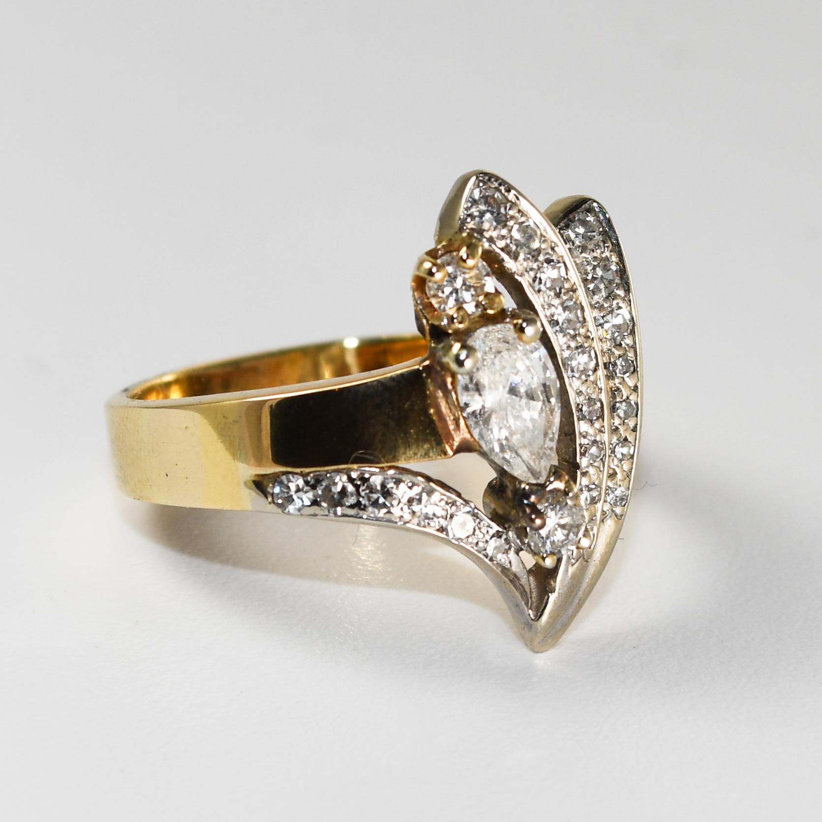 This cluster style 14 karat yellow gold ring weighs 7.50 grams.
It contains a 6x4mm pear-shaped diamond, with a carat weight of 0.40, SI2 clarity, and g-h-i  color.
This is accented by an additional twenty-two round brilliant diamond, with a carat