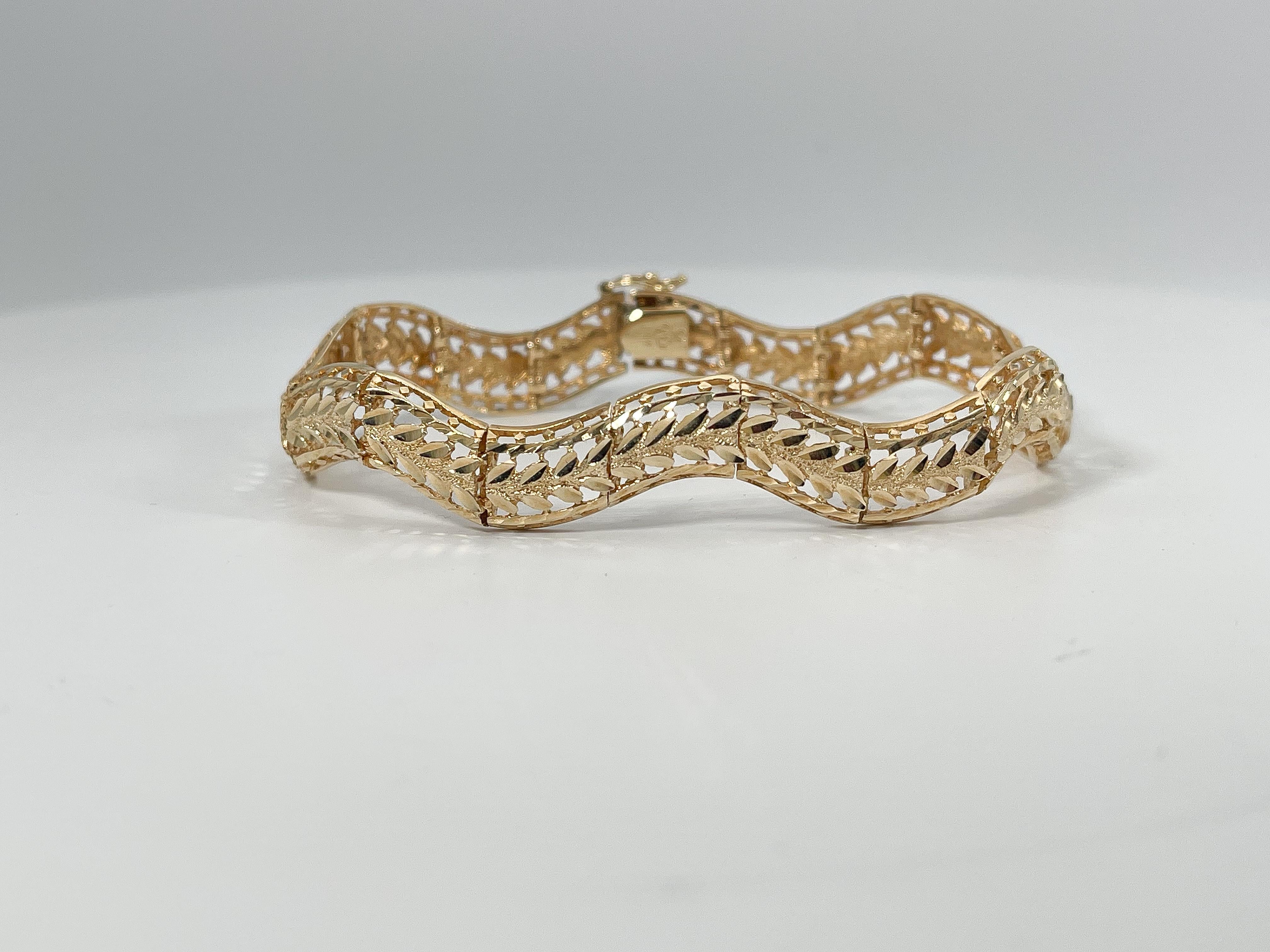 141k yellow gold diamond cut wave bracelet. This bracelet has a figure 8 clasp to open and close, the width is 8.5 mm, the length is 7.5 inches, and the total weight is 14.38 grams.