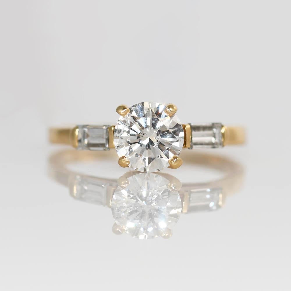 Bague de fiançailles pour dames en diamant avec monture en or jaune 14k.
Estampillé 14k et pèse 2,7 grammes.
Le diamant central est un diamant rond de 1,03 carat de taille brillant, de couleur F à G et de pureté i1.
Sur les côtés se trouvent deux