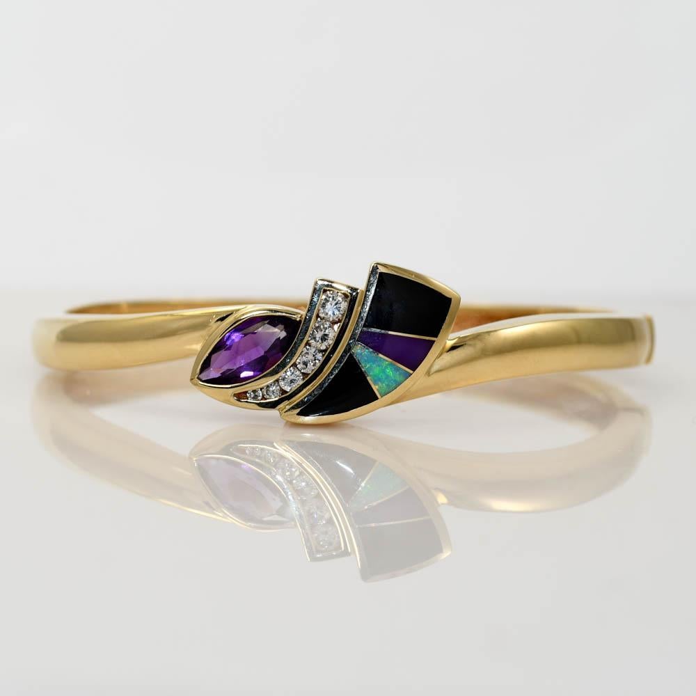 Custom 14k yellow gold bangle bracelet.
Set with diamonds, black onyx, opal and amethyst.
Stamped 14k and weighs 29.2 grams gross weight.
The diamonds are round brilliant cuts, .30 total carats, i to j color, Si clarity.
The bracelet measures 16mm