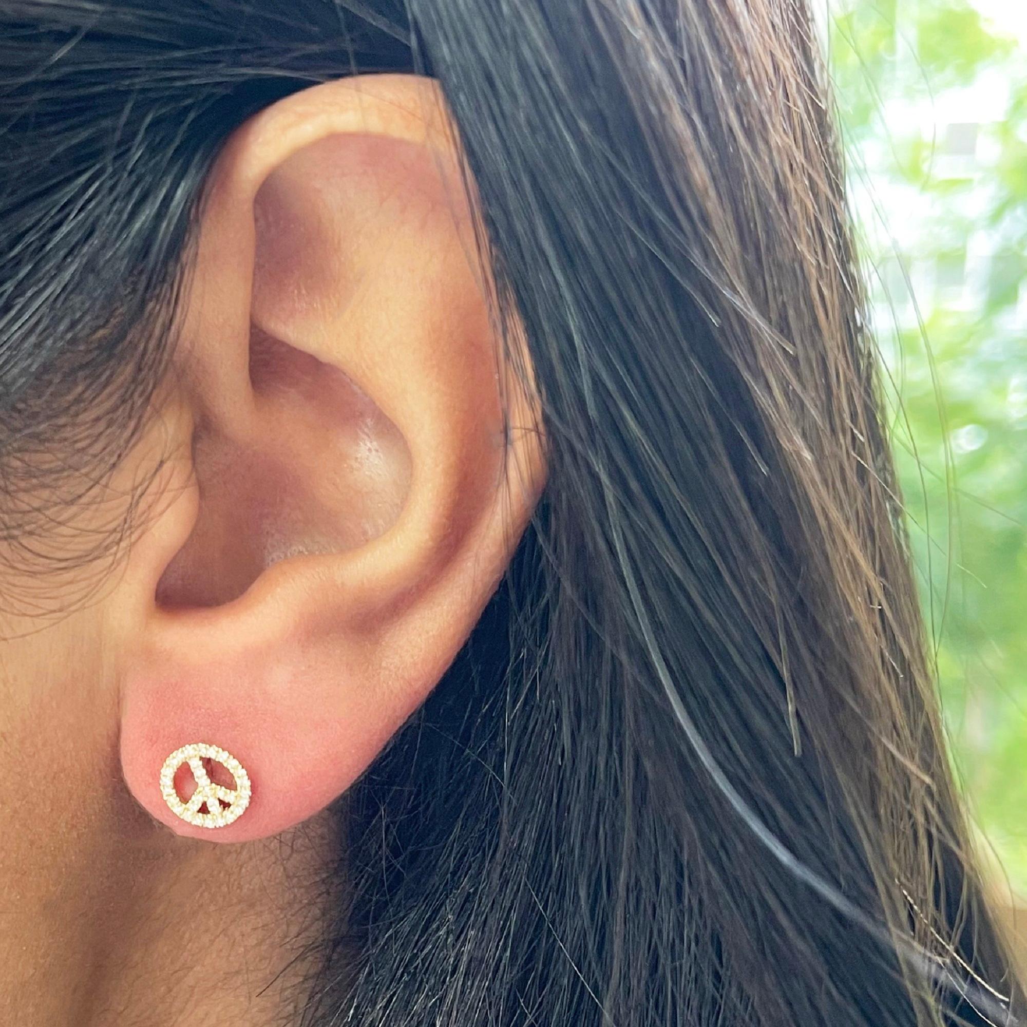 Peace Sign Earrings: Crafted of real 14k gold, these popular Peace Sign shape earrings feature 64 natural white sparkling diamonds approximately 0.18 ct. Certified diamonds. Diamond Color & Clarity GH-SI1 Measures approximately 1/2 Inch. Secured