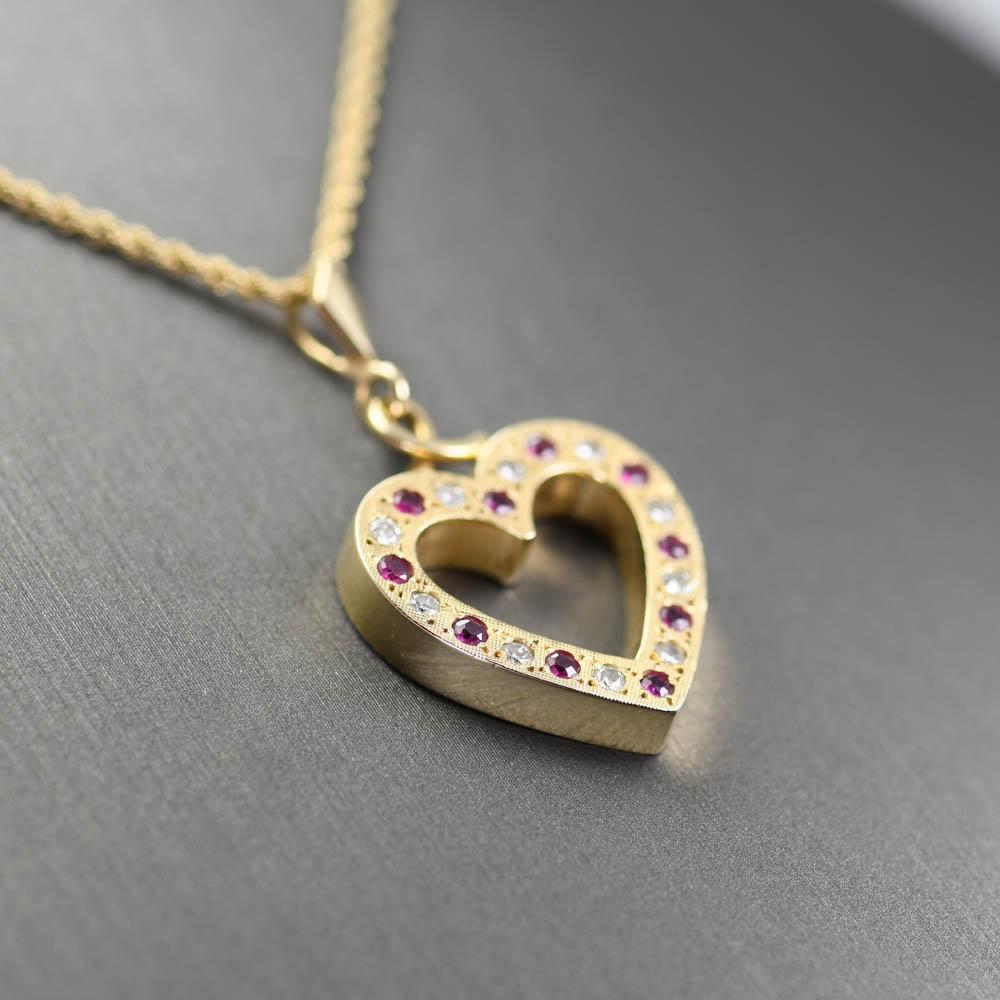 Collana con ciondolo a cuore in oro giallo con diamanti e rubini.
Test 14k e peso di 9 grammi.
I diamanti sono tagli tondi brillanti, 0,30 carati totali, colore da H a I, purezza Si.
I rubini naturali sono tagli tondi brillanti, 0,30 carati totali,