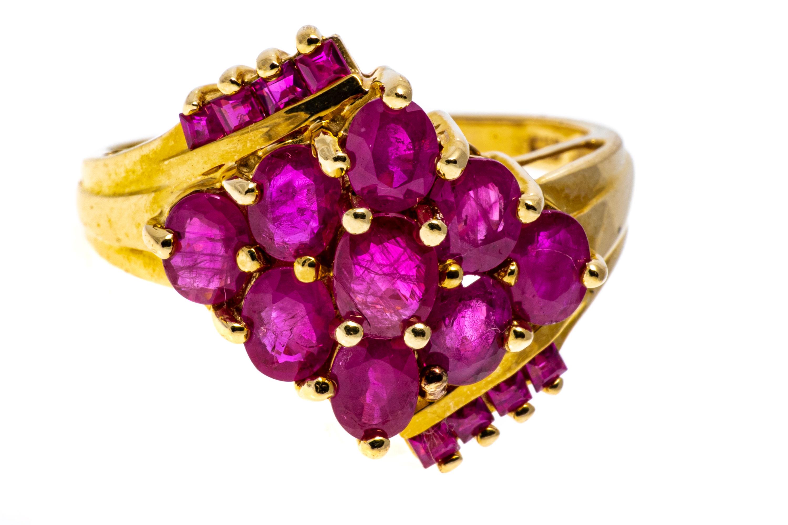 14k yellow gold ring. This striking yellow gold ring is a diamond shaped bypass cluster style, set with a center of oval faceted, reddish pink color rubies, approximately 1.16 TCW, prong set. Offsetting the center is a row of square faceted, reddish