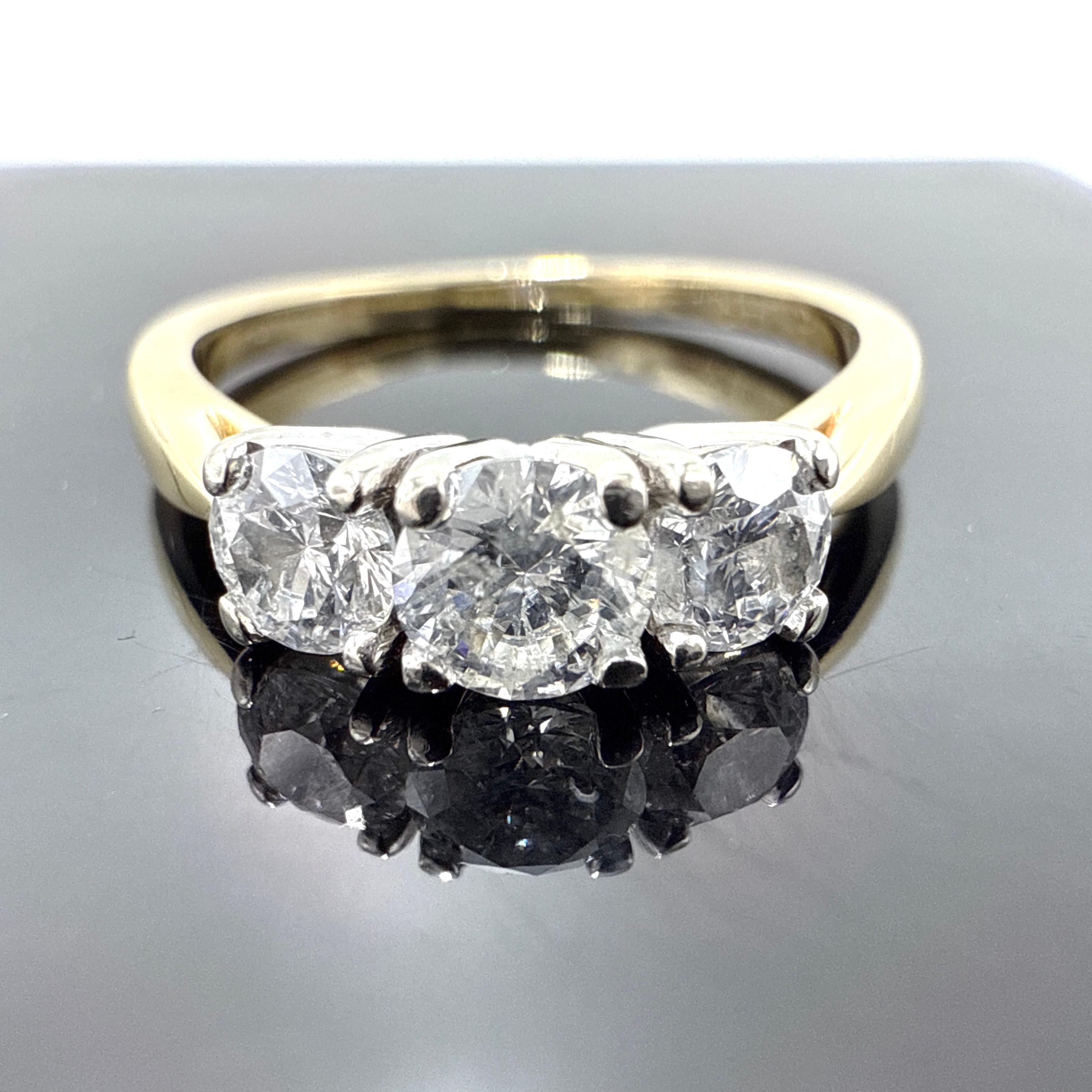 Il s'agit d'une bague trinitaire en or jaune 14K, coulée à la cire, assemblée à la main et finie avec une surface polie. Le modèle présente un arrangement horizontal de trois diamants ronds de taille brillant dans des montures à quatre griffes en or