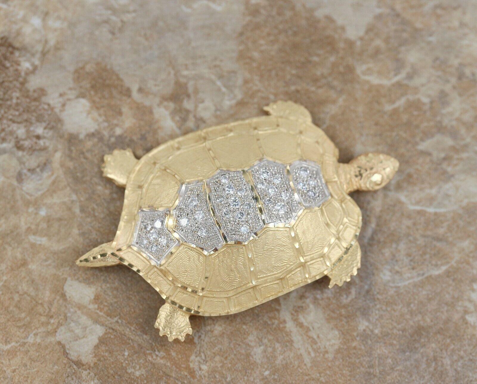 Ce magnifique pendentif est réalisé dans un or jaune 14k brillant et structuré, avec des accents de rhodium. Le centre de la carapace de la tortue est orné de trente diamants ronds brillants en serti clos. Avec une attache à la fois sur le dessous