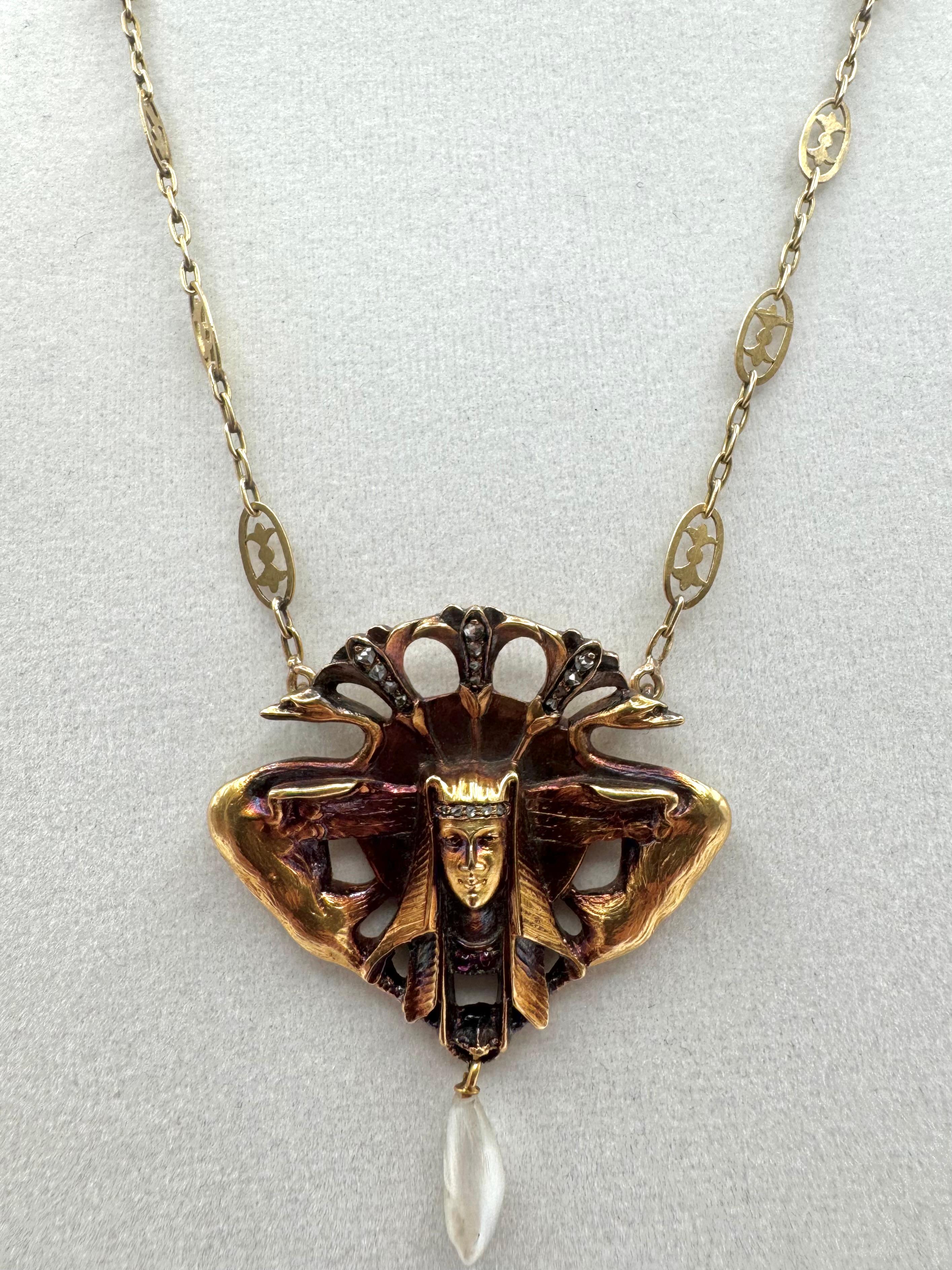A striking example of Egyptian Revival artistry, this 14K yellow gold necklace features a highly detailed pharaoh motif pendant adorned with old-cut diamonds, ruby accents, and a luminous pearl drop. The pharaoh's headdress is flanked by stylized